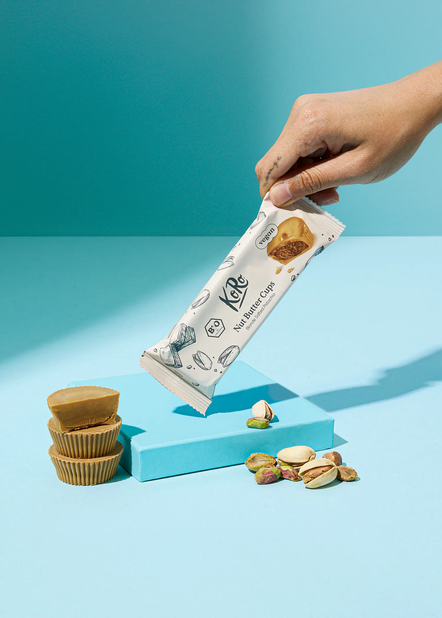 une personne tient une barre de beurre de noix avec des pistaches dessus