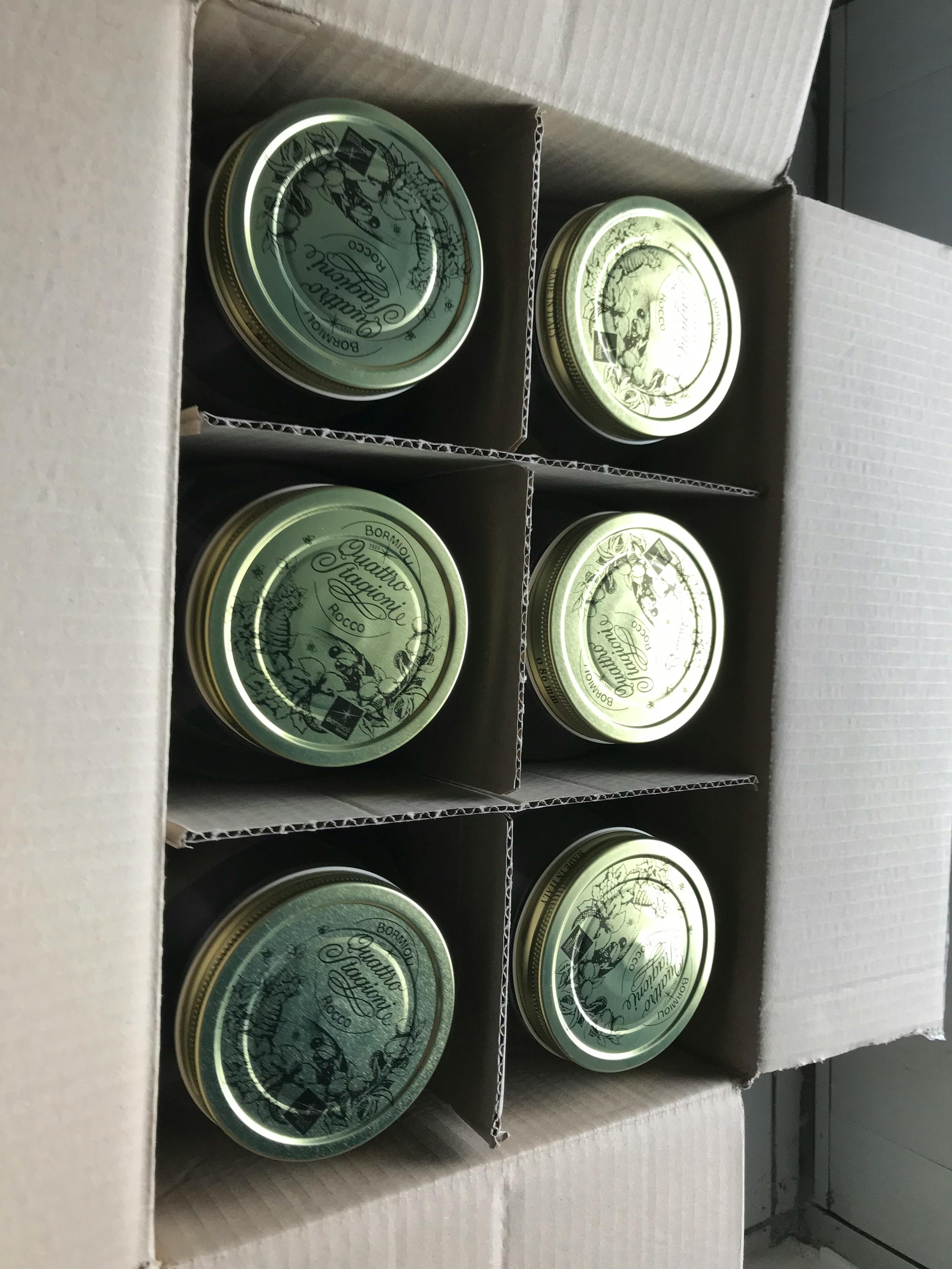 eine Schachtel mit sechs Gläsern mit goldenen Deckeln ..