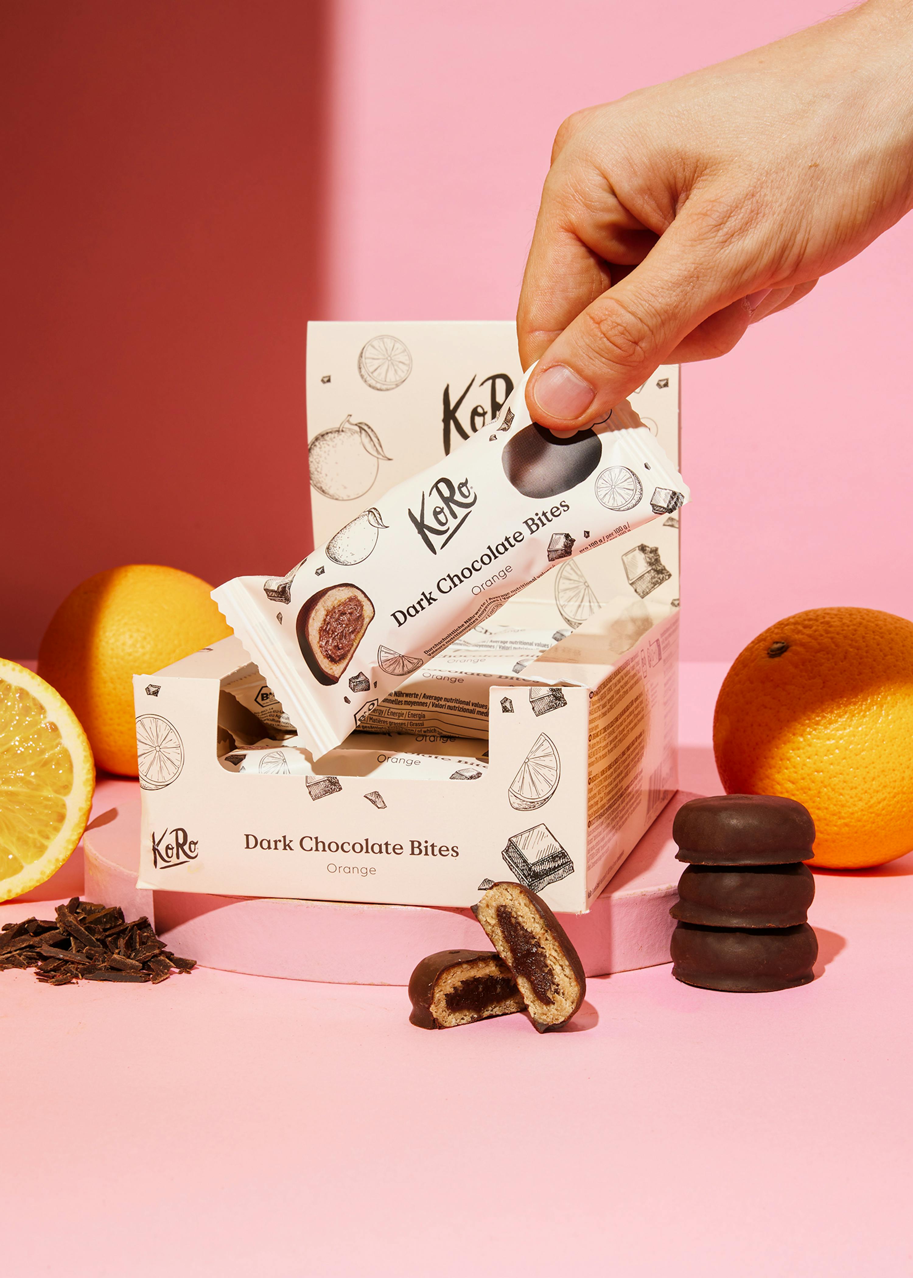 une personne tient une barre de chocolat noir à côté d' une boîte