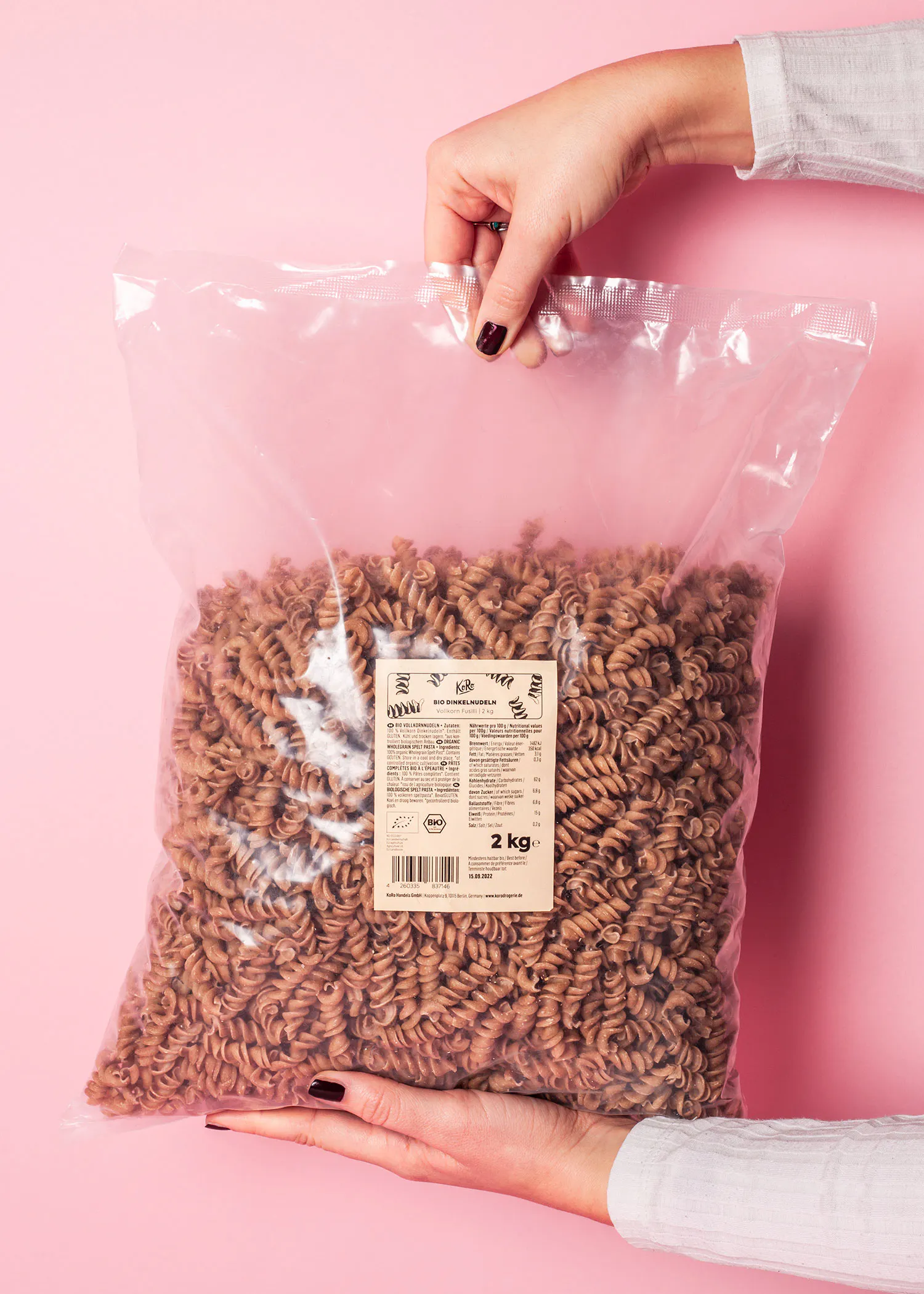 a woman is holding a bag of pasta that is 2 kg