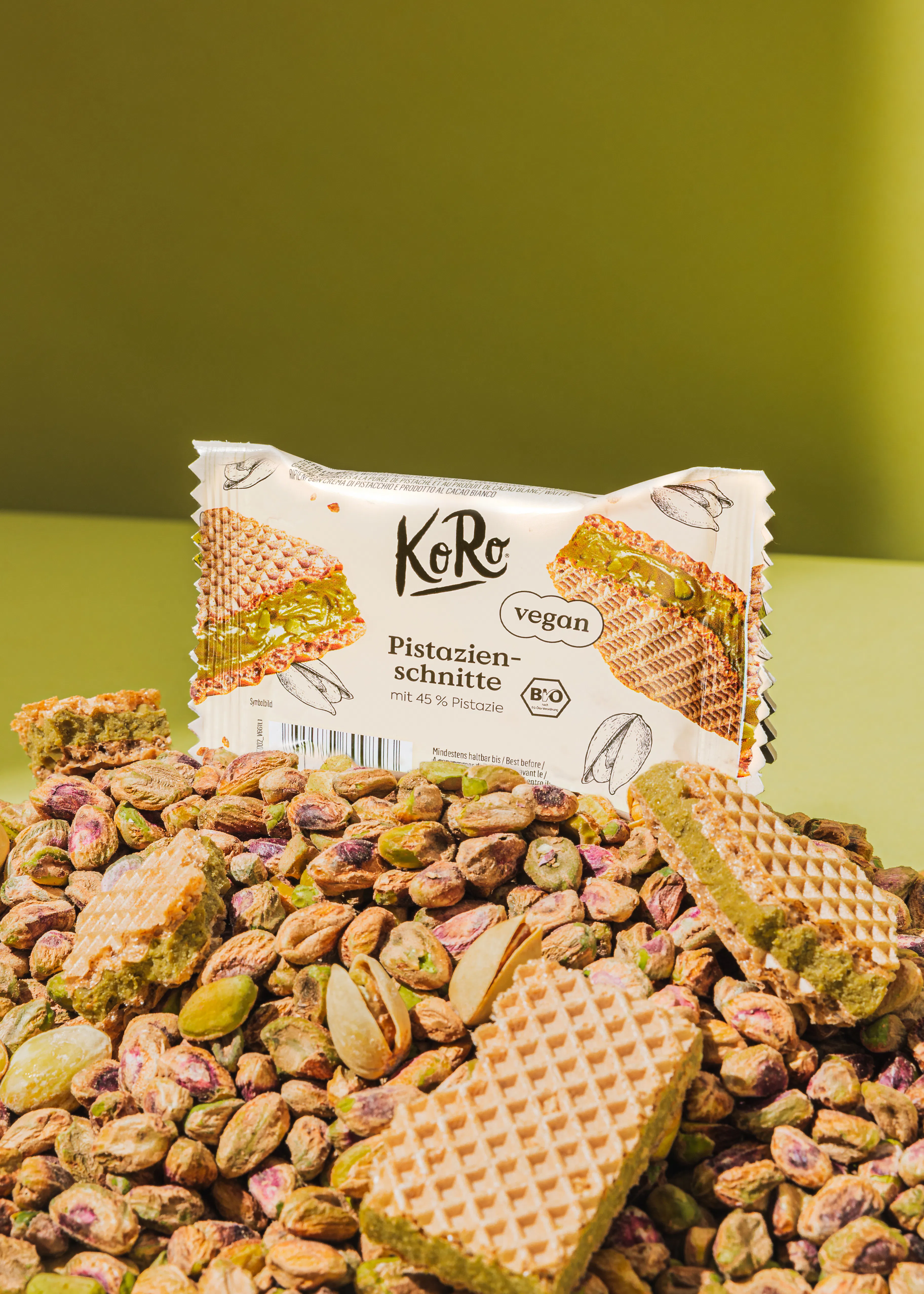 une barre de chocolat végétalien posée sur une pile de pistaches