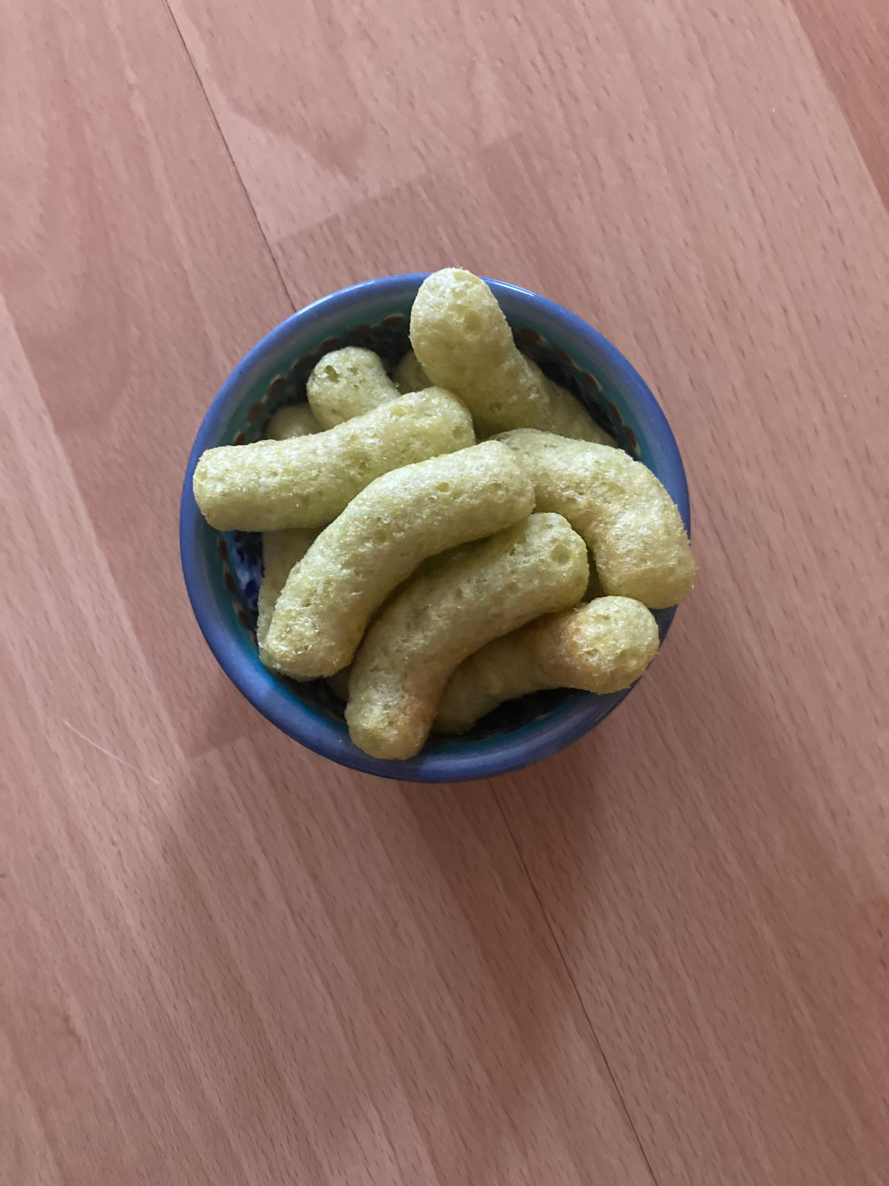 una ciotola blu piena di bastoncini verdi su un tavolo di legno
