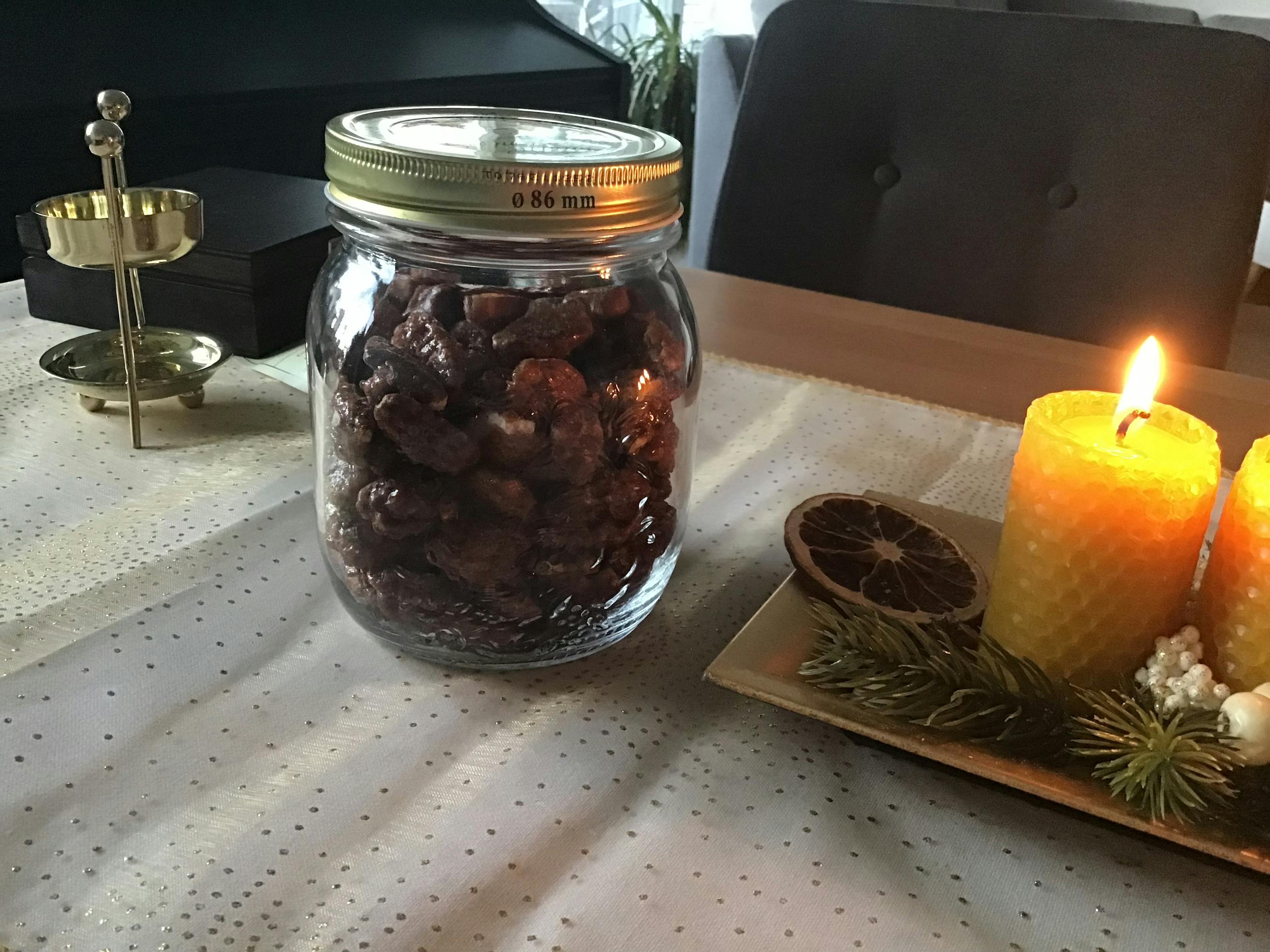 a jar of nuts sits on a table next to a lit candle