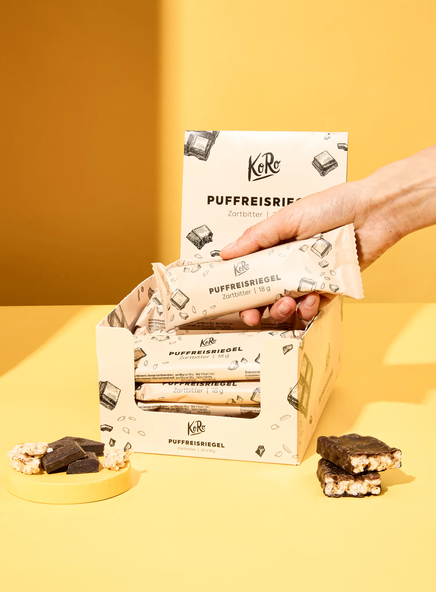 une personne tient une barre de chocolat à côté d' une boîte