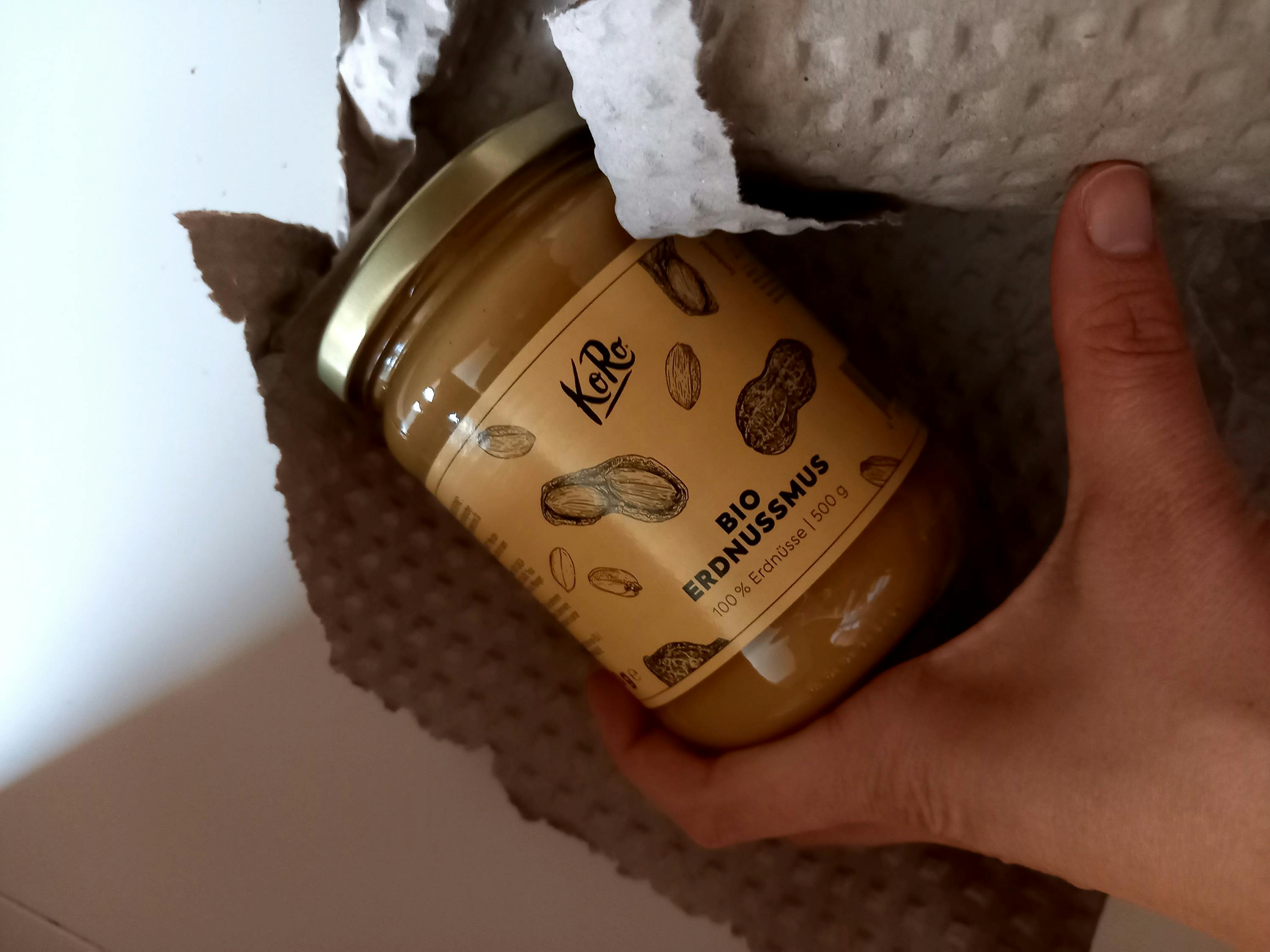 a person is holding a jar of erdnussmus in their hand