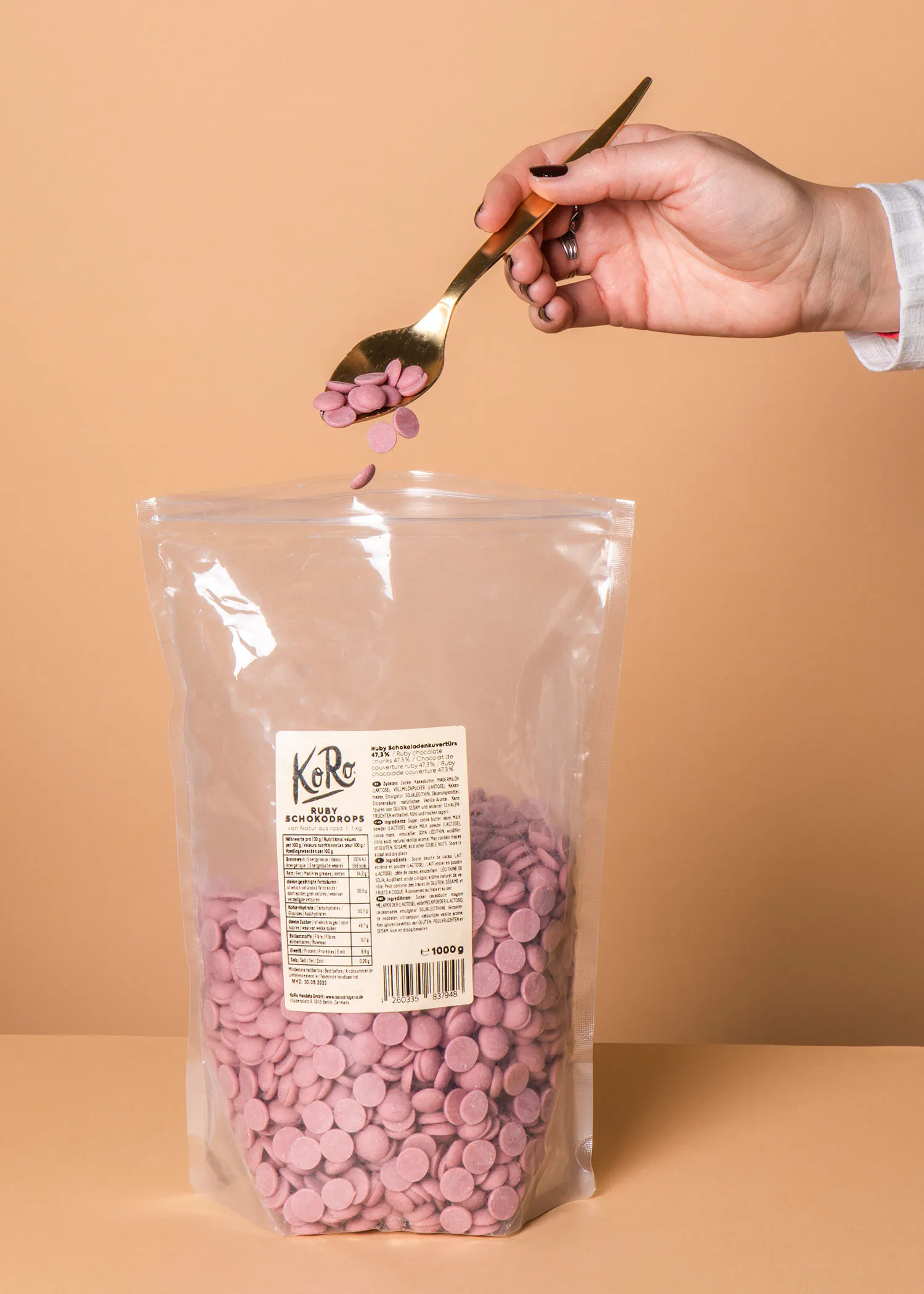 une personne tient une cuillère à côté d' un sac de pépites de chocolat rose