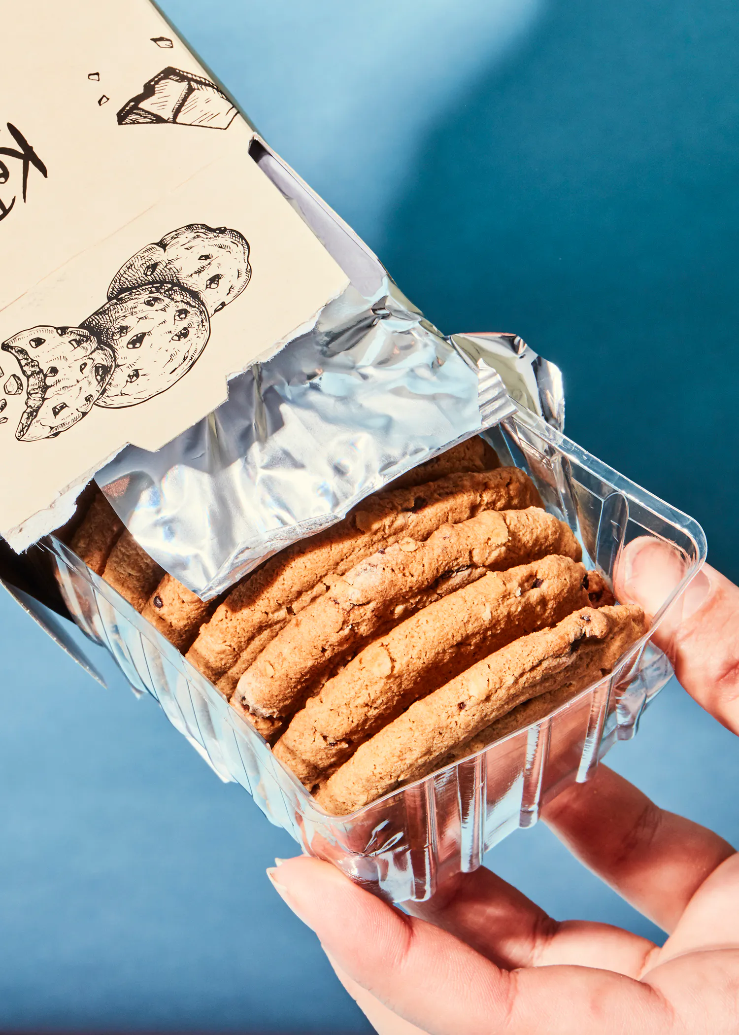 une personne tient une boîte de biscuits en plastique dans sa main