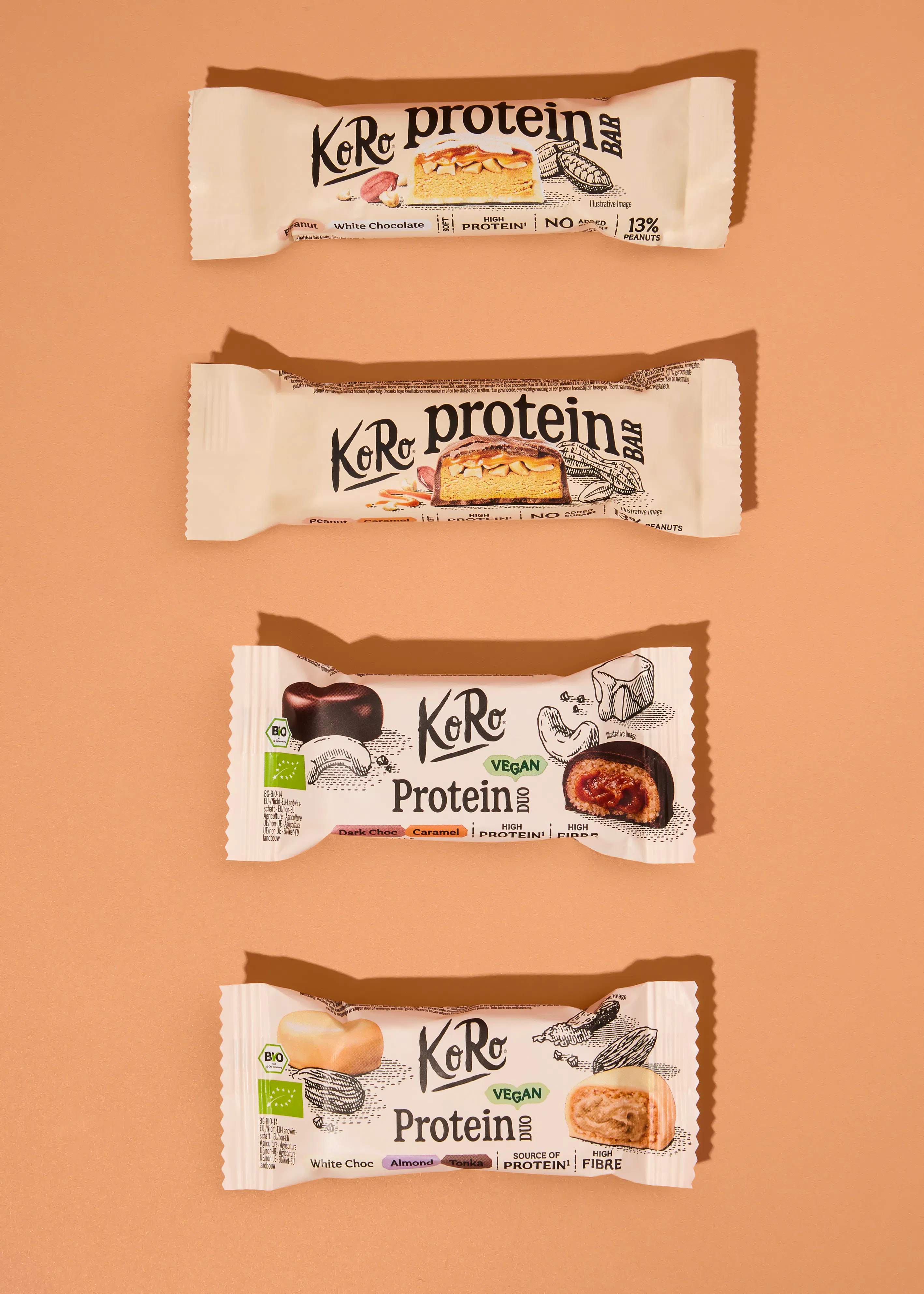 quattro barrette proteiche koro disposte verticalmente su uno sfondo color sabbia, ognuna con il proprio incarto distintivo che mostra il gusto e gli ingredienti.