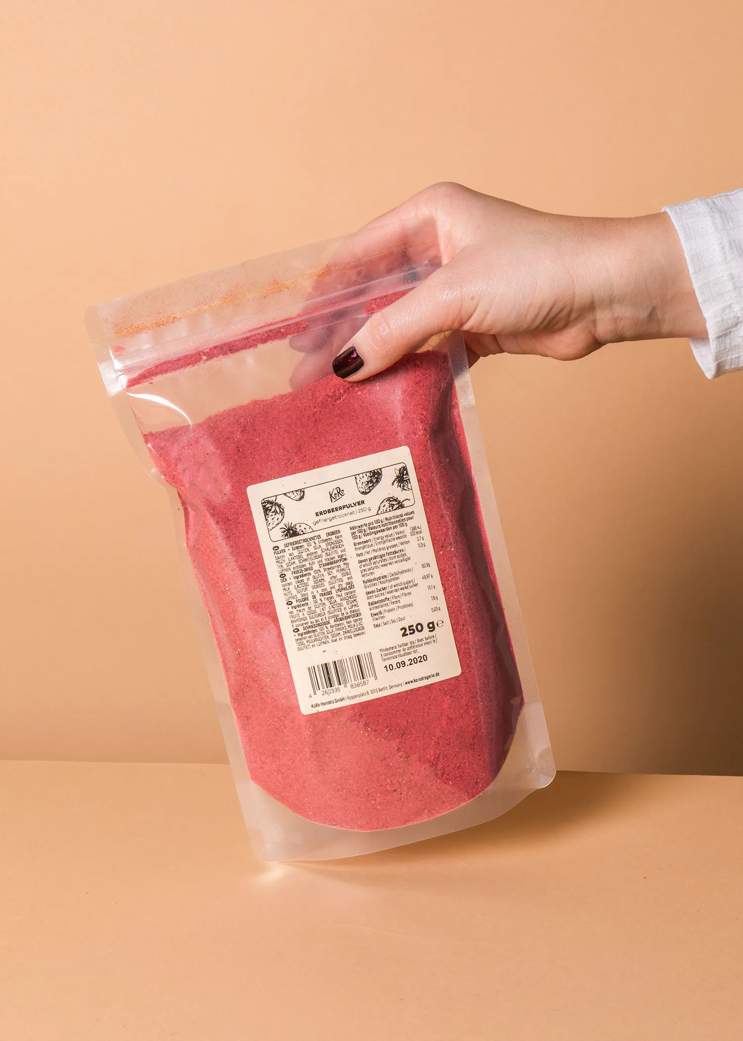 une personne tient un sac de poudre rouge avec une étiquette blanche