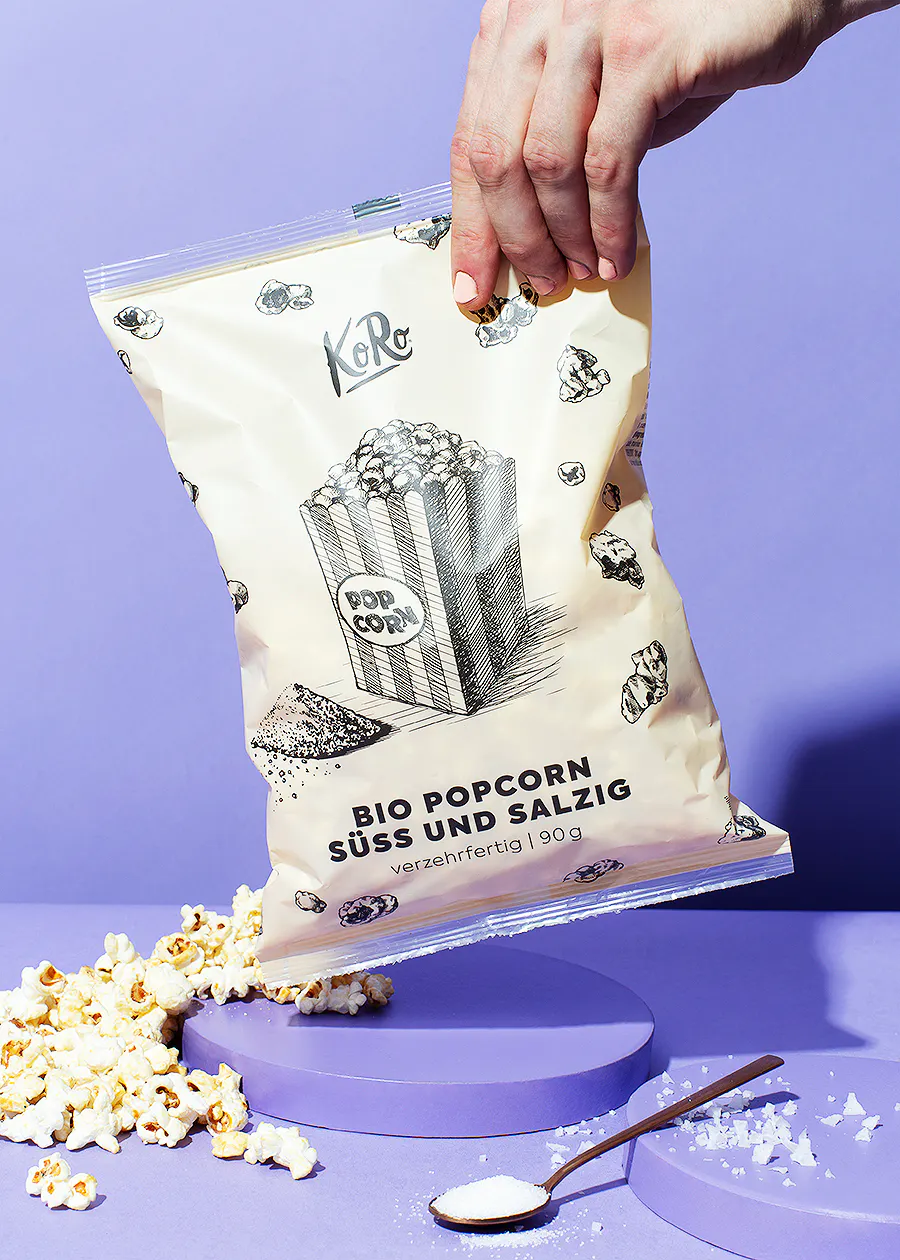 une personne tient un sac de pop-corn bio sur un fond violet