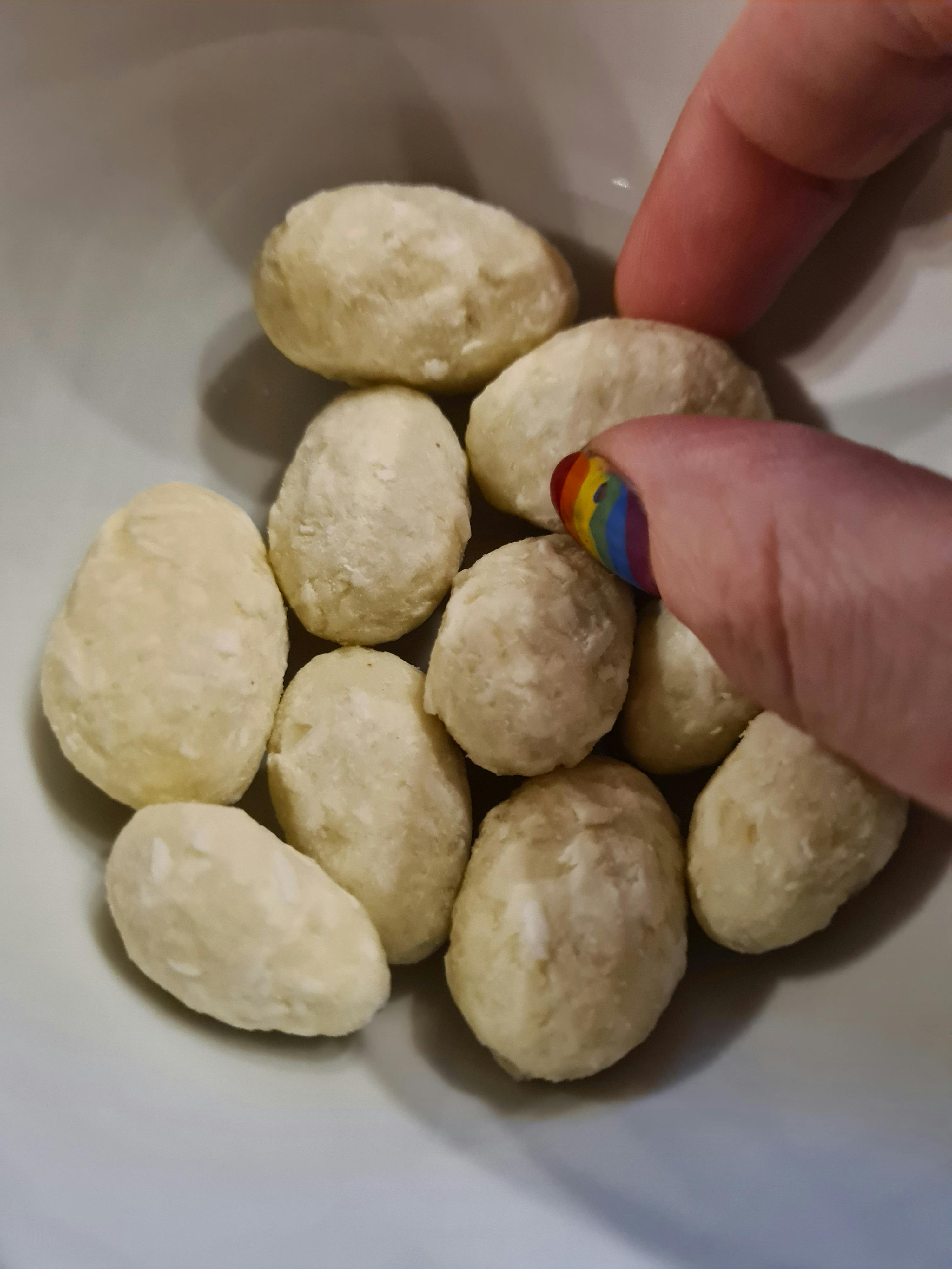 Eine Person hält einen Regenbogen-Nagelstift über einer Schüssel mit Bällchen