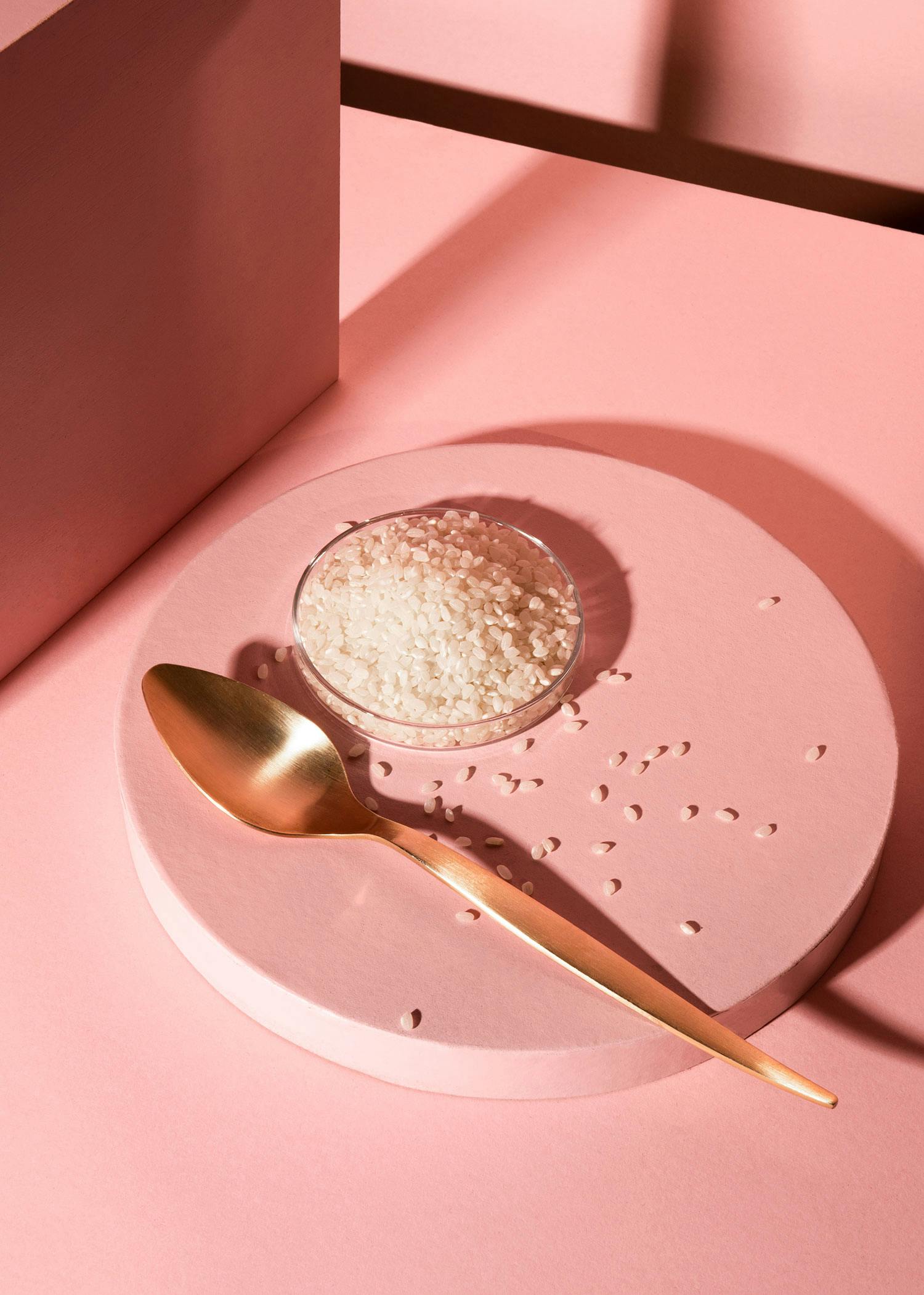 a gold spoon sits next to a petri dish of rice