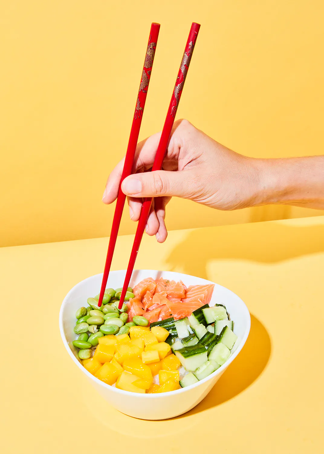 a person is holding chopsticks over a bowl of food