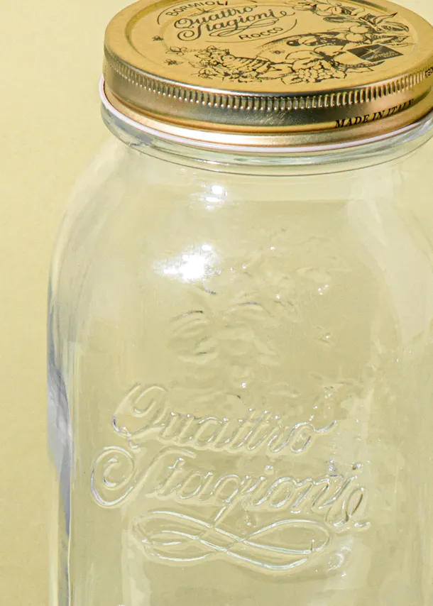 ein Glasgefäß mit einem goldenen Deckel und der Aufschrift quattro stagioni