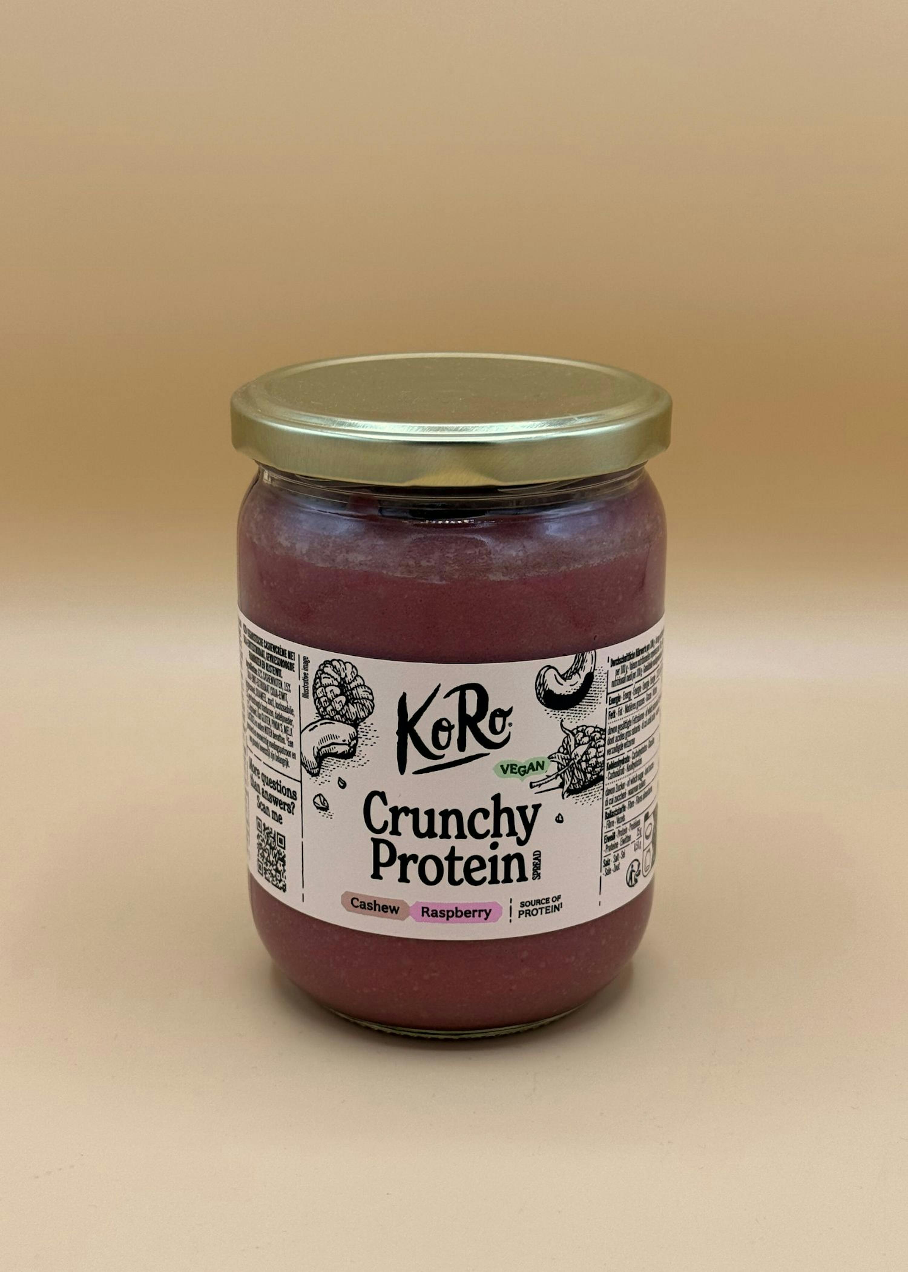 a jar of koro crunchy protein vegan spread, made with cashew and raspberry, on a plain background.