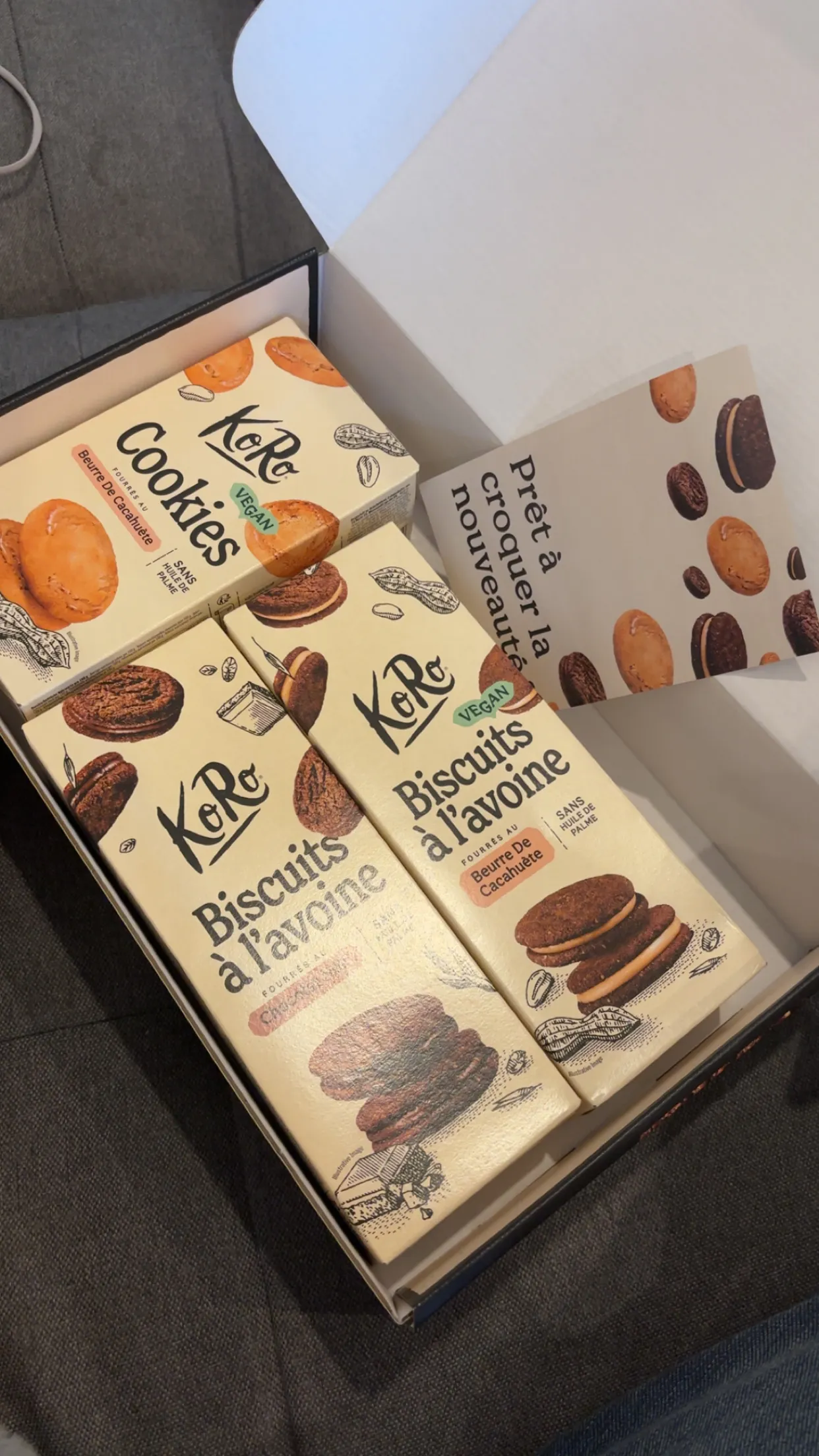 eine offene geschenkbox mit drei packungen koro-keksen und einer grußkarte.