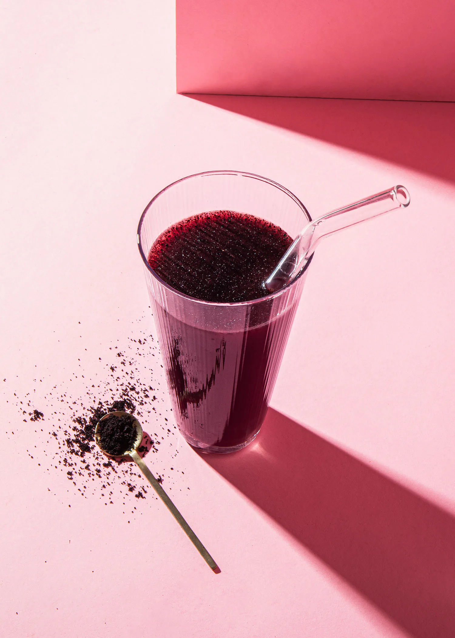 un verre de boisson rouge avec une paille et une cuillère