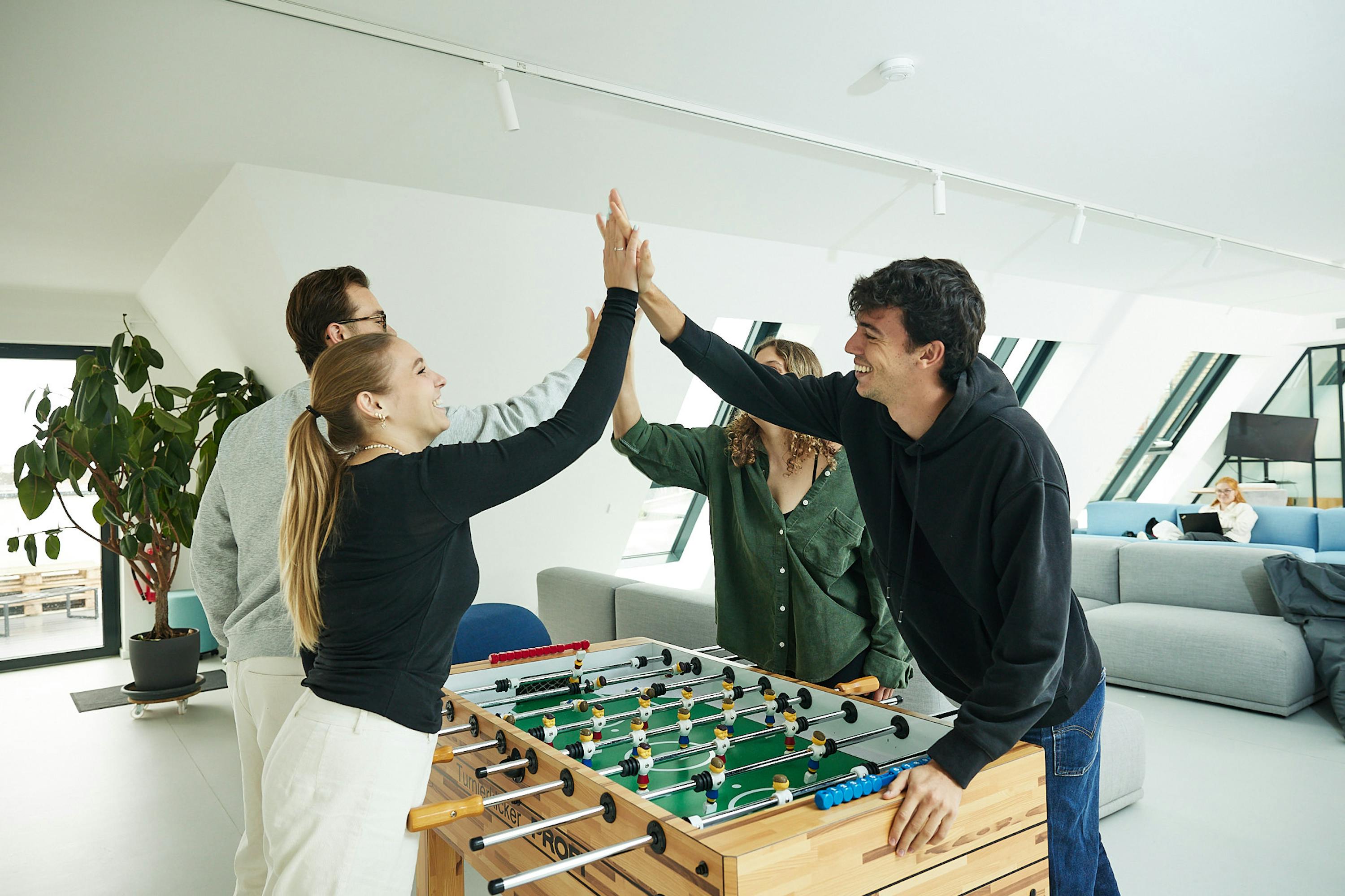 un gruppo di persone si dà il cinque mentre giocano a calcio balilla