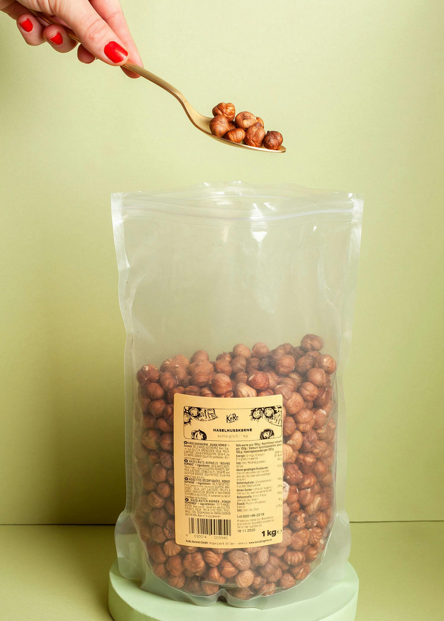 una persona tiene in mano un cucchiaio pieno di nocciole sopra un sacchetto di nocciole