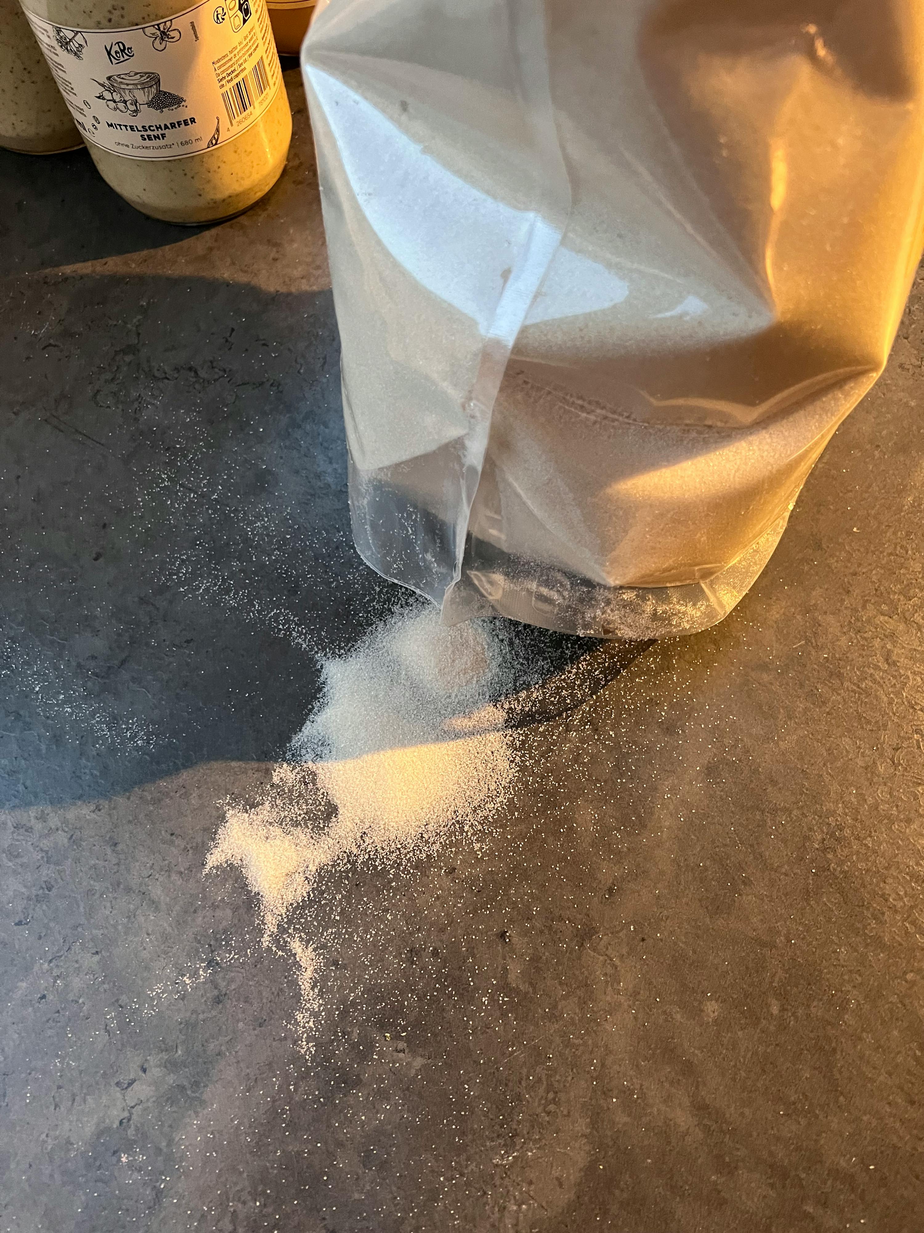a bag of flour is being poured into a jar of mustard