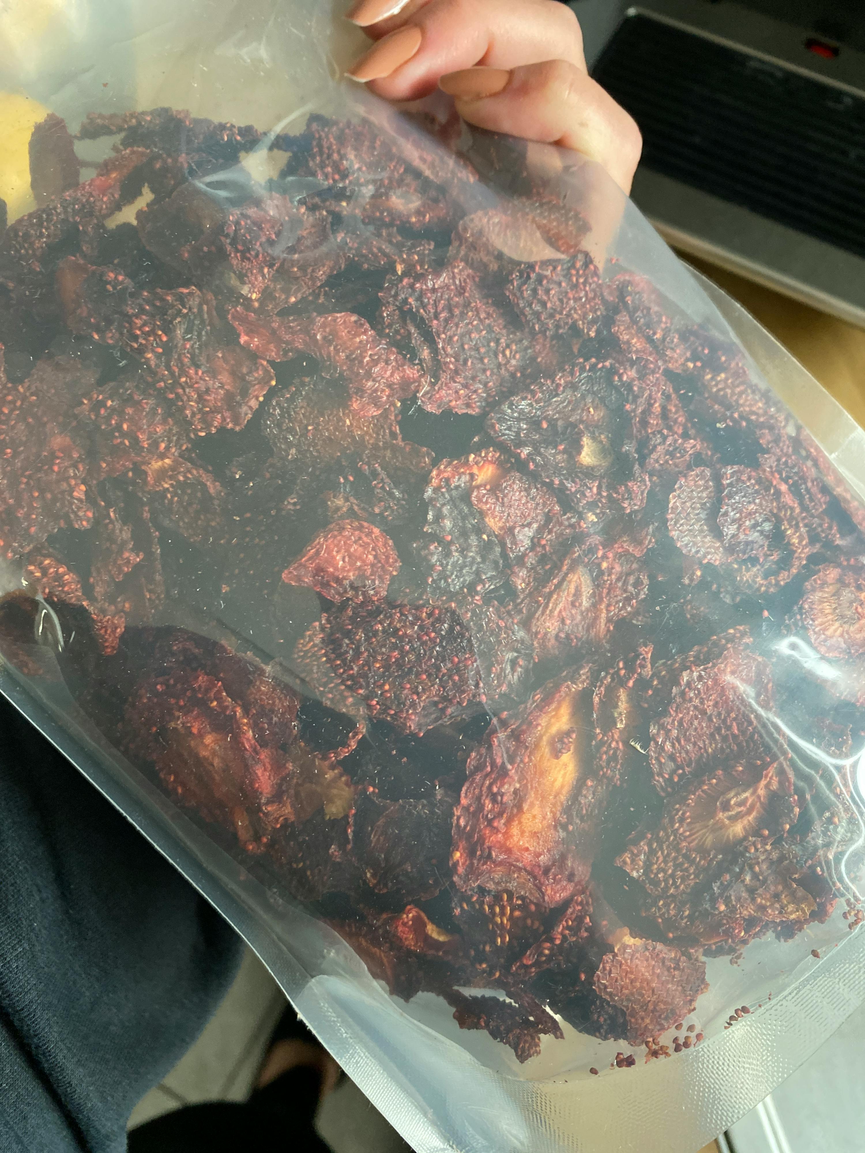 a person is holding a bag of dried fruit