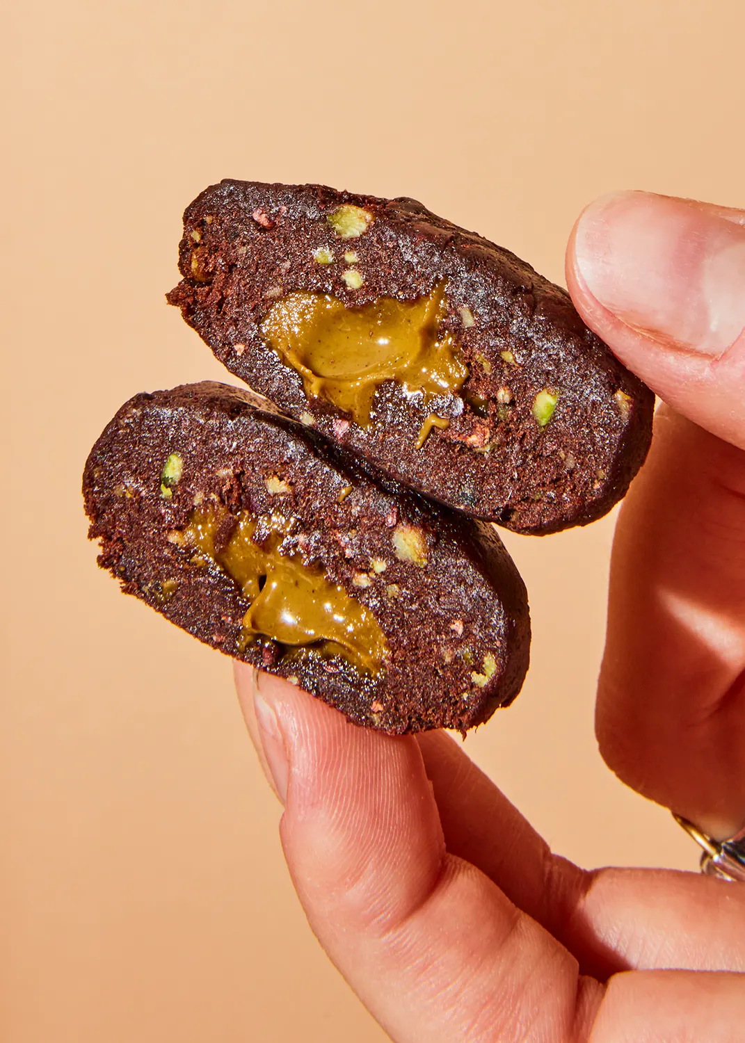 une personne tient deux morceaux de gâteau au chocolat avec du caramel à l' intérieur