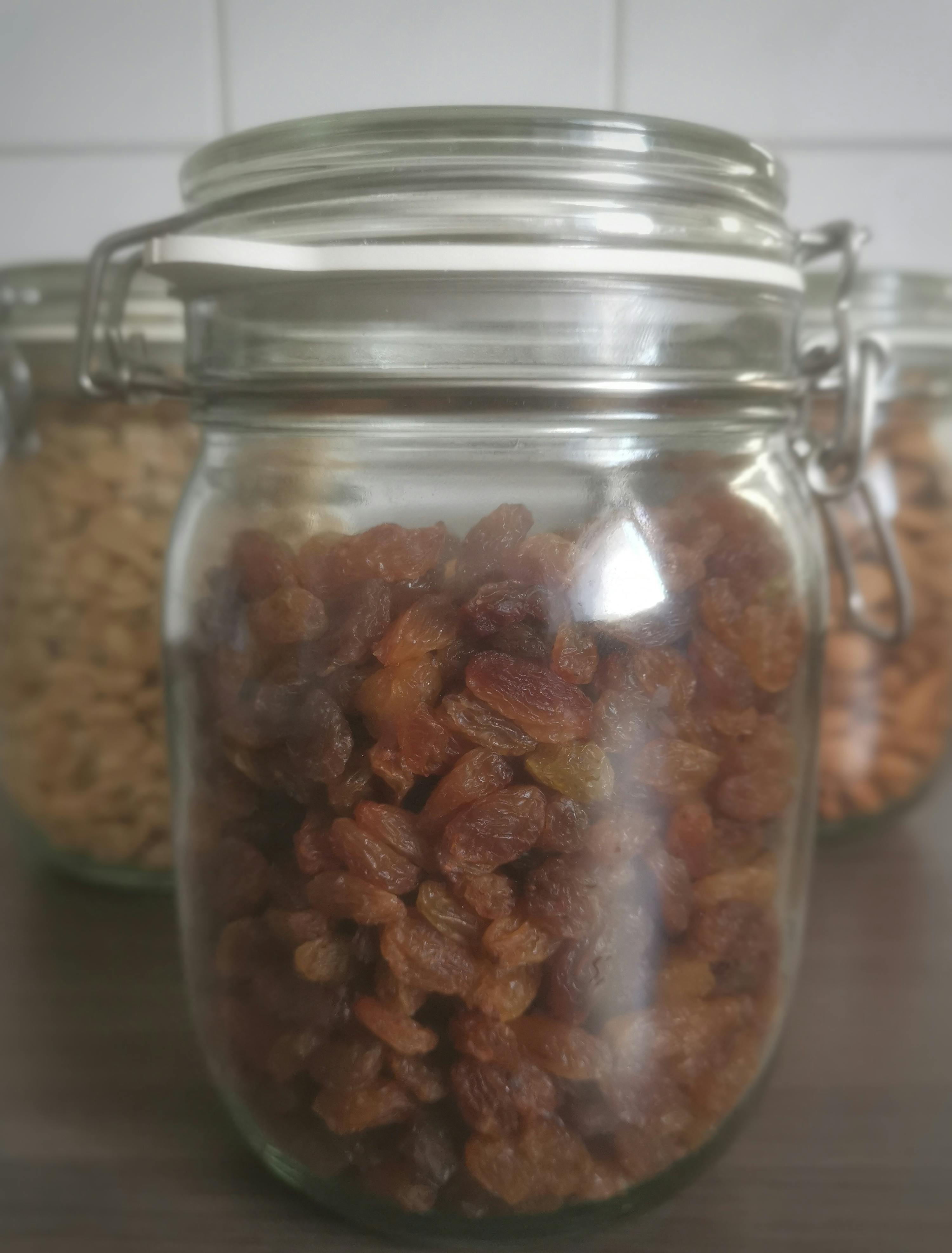un bocal en verre rempli de raisins est assis sur une table