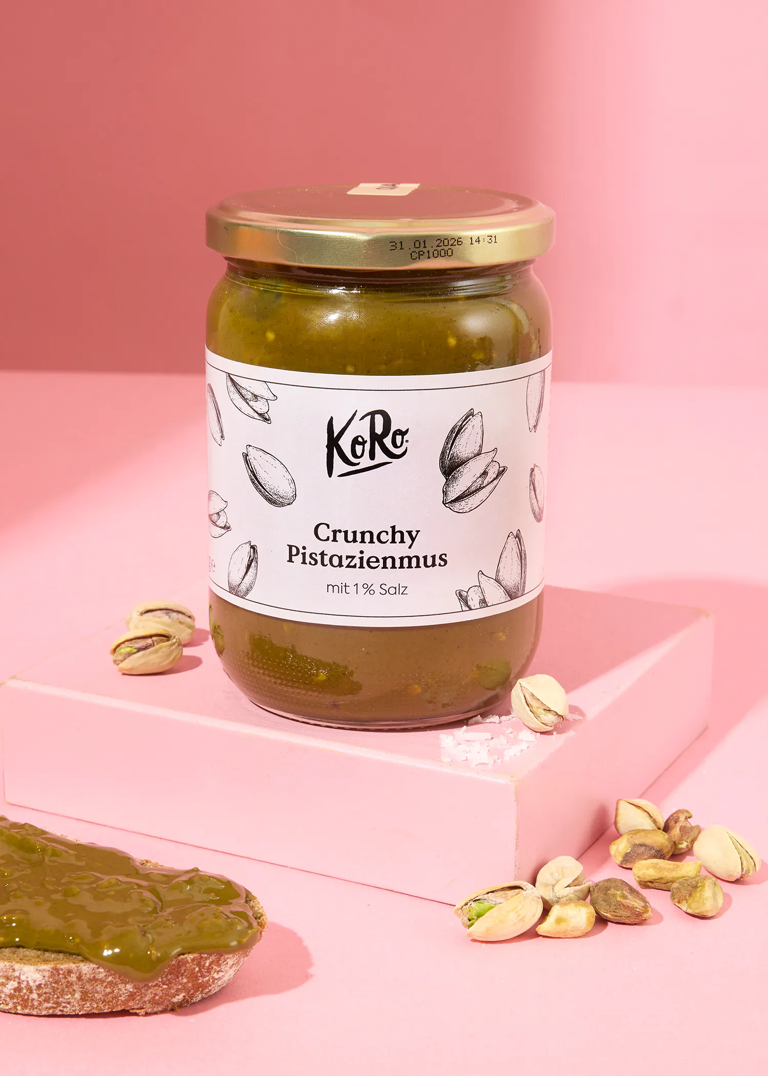 un bocal de crunchy pistazienmus est posé sur une table rose