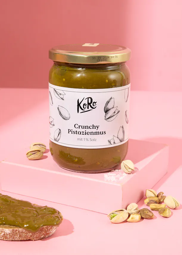 un bocal de crunchy pistazienmus est posé sur une table rose