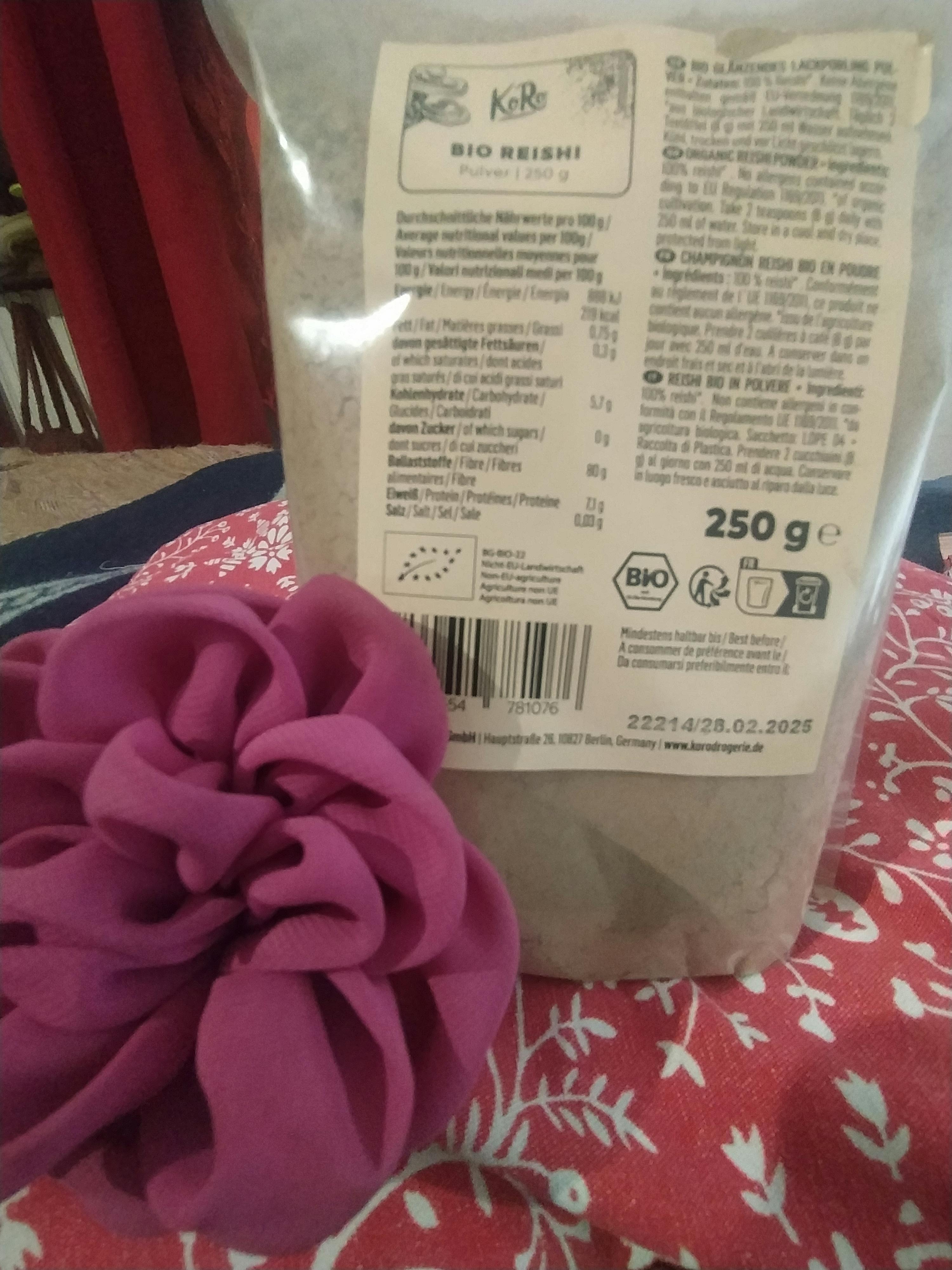 eine lila Blume sitzt neben einem 250g-Beutel