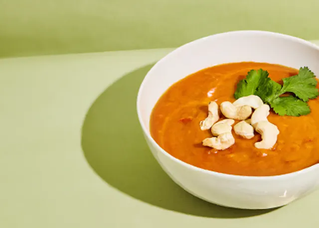 a bowl of soup with cashews and parsley on top