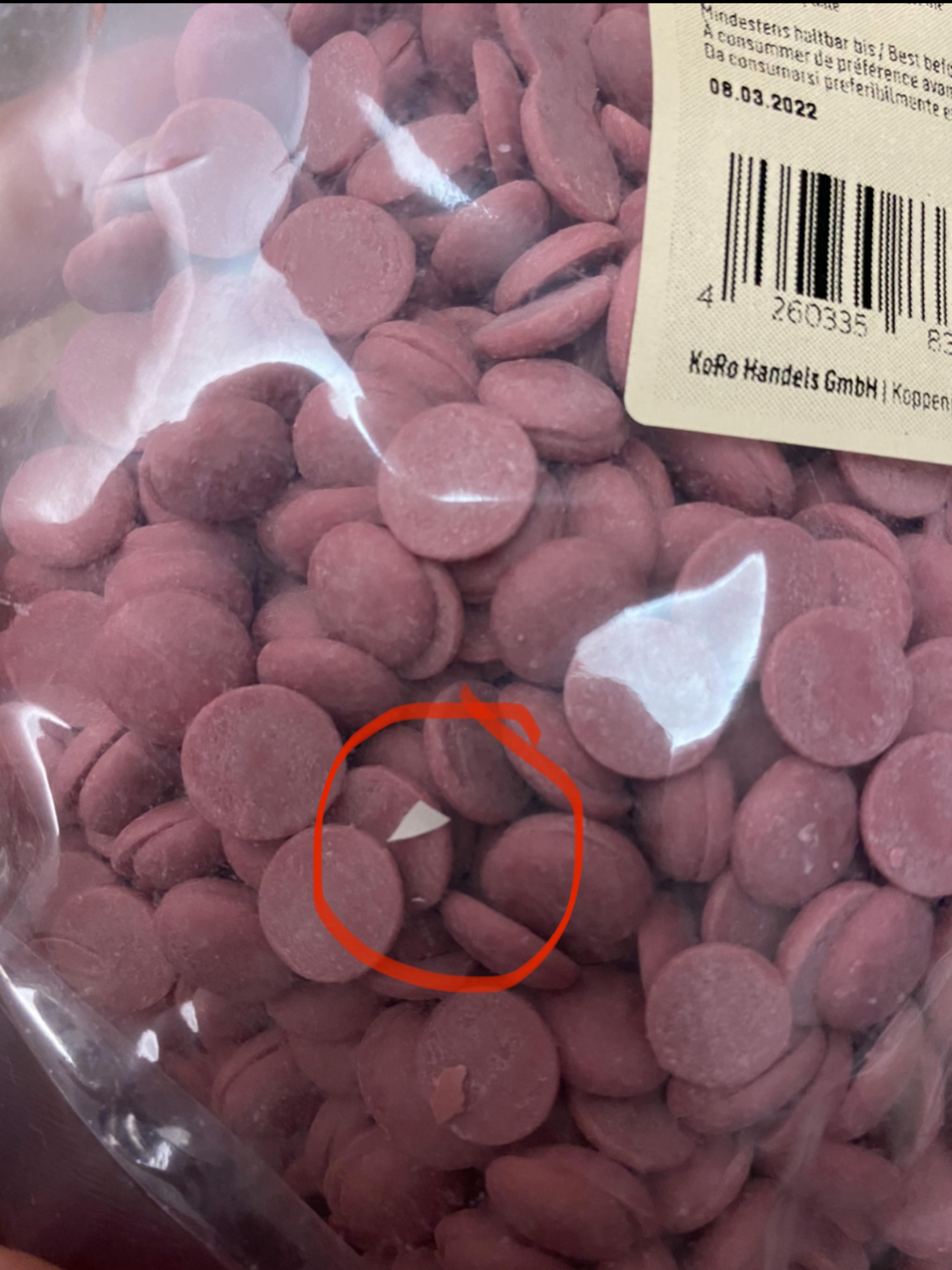 ein Plastikbeutel mit rosa Schokoladenstücken mit einem roten Kreis darauf