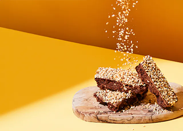 ein Holzschneidebrett mit einem Stapel Schokoladenbrownies darauf