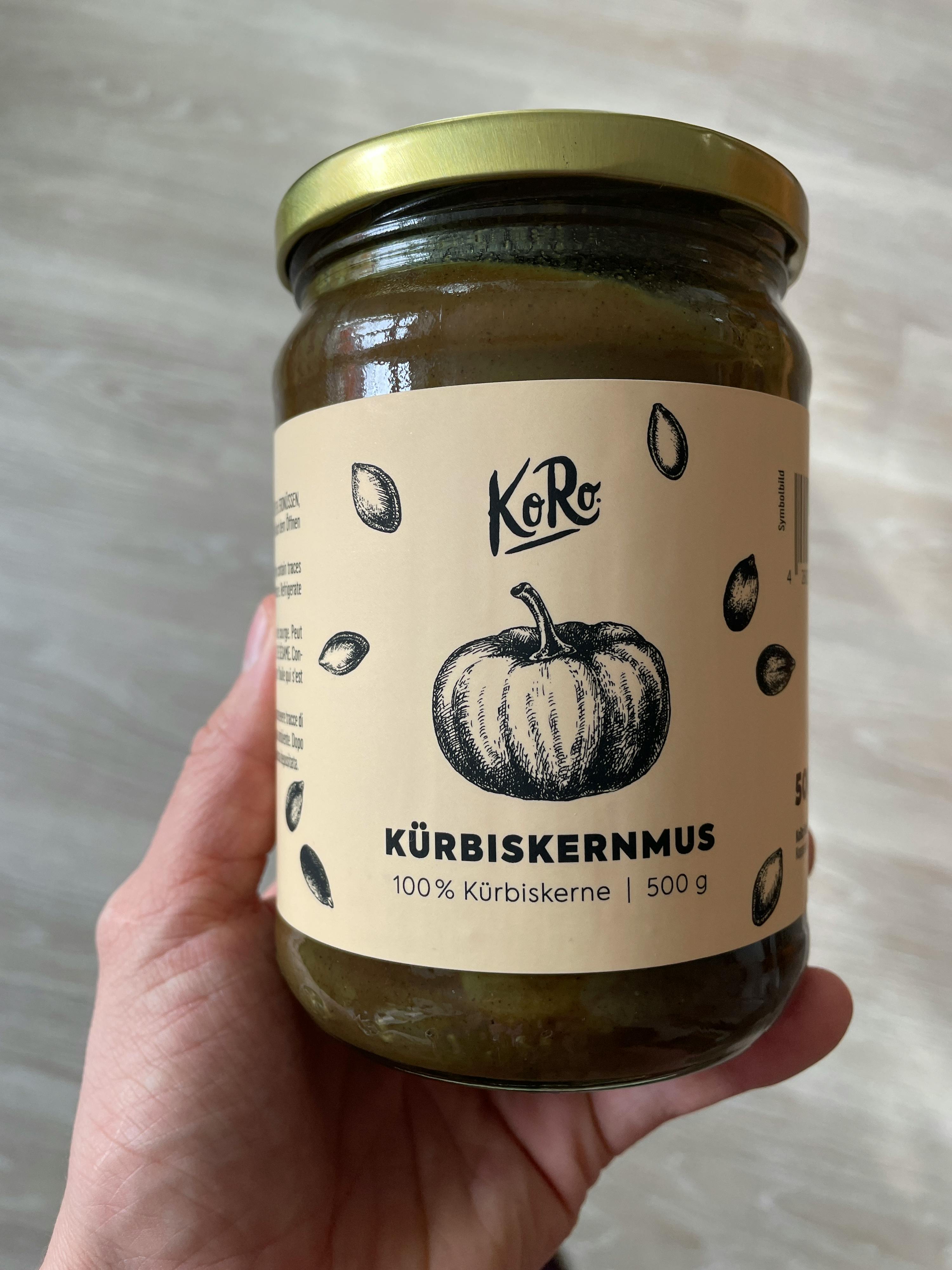 a person is holding a jar of kurbiskernmus in their hand