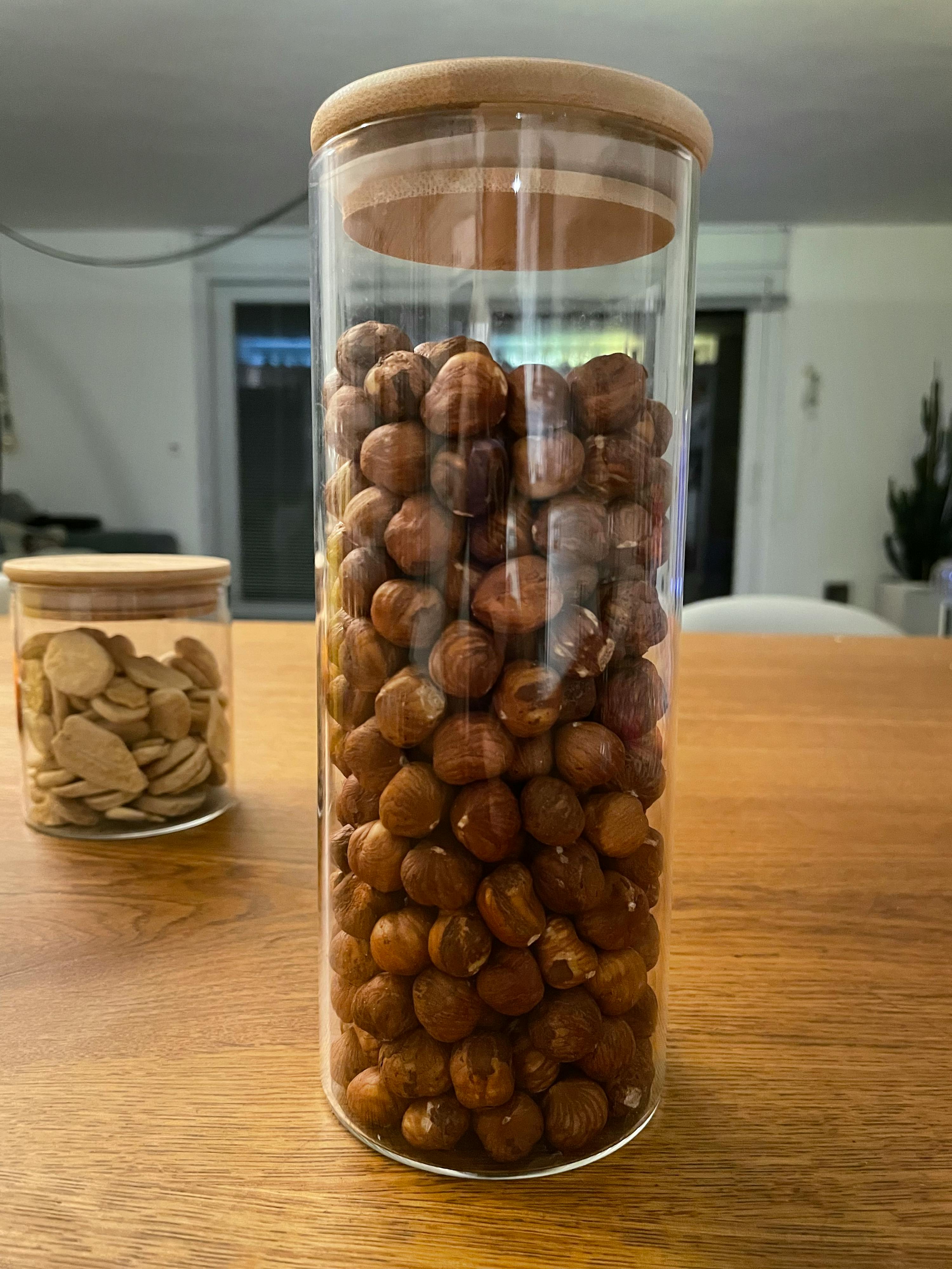 un barattolo di vetro pieno di nocciole su un tavolo di legno