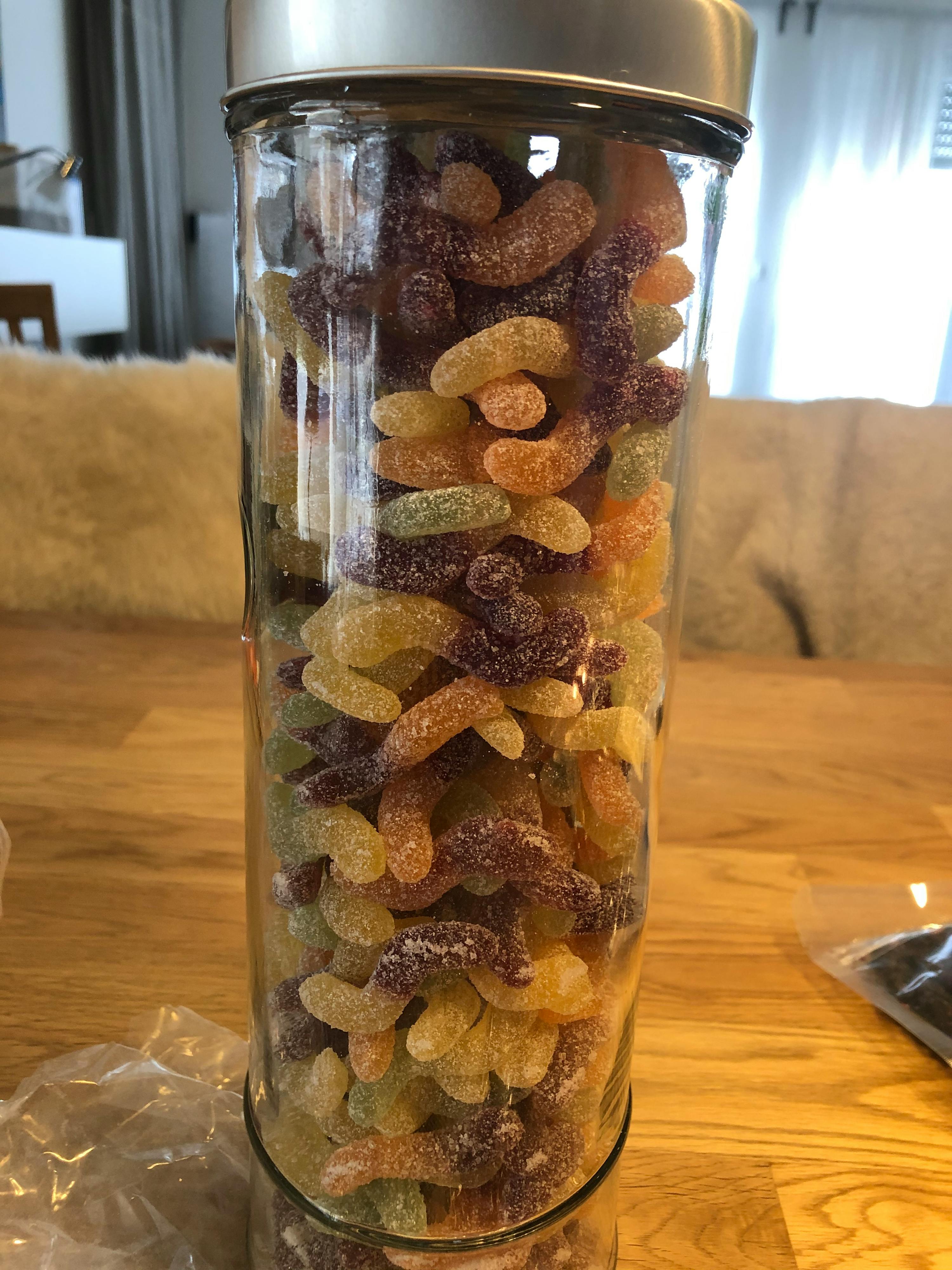 ein Glas gefüllt mit bunten Süßigkeiten auf einem Holztisch