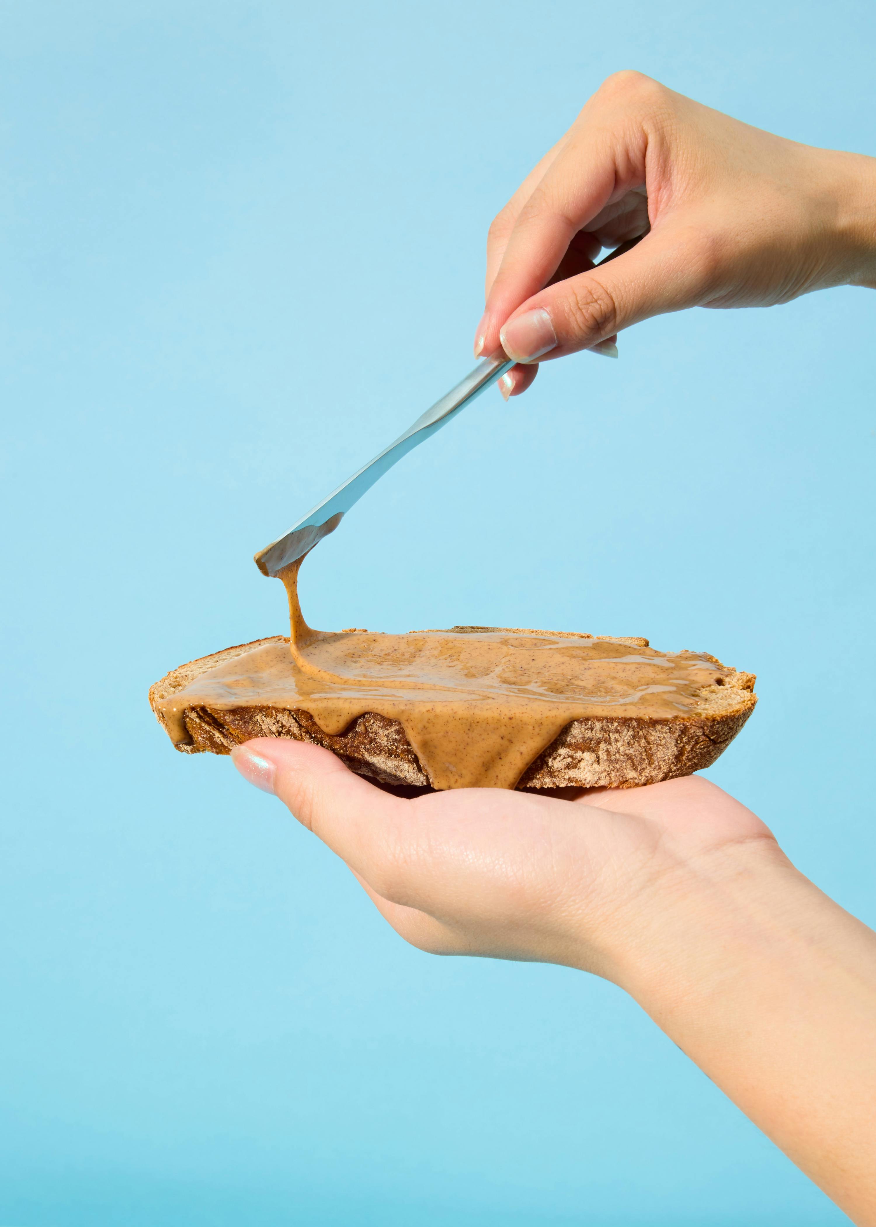 eine Person spreads Erdnussbutter auf ein Stück Brot