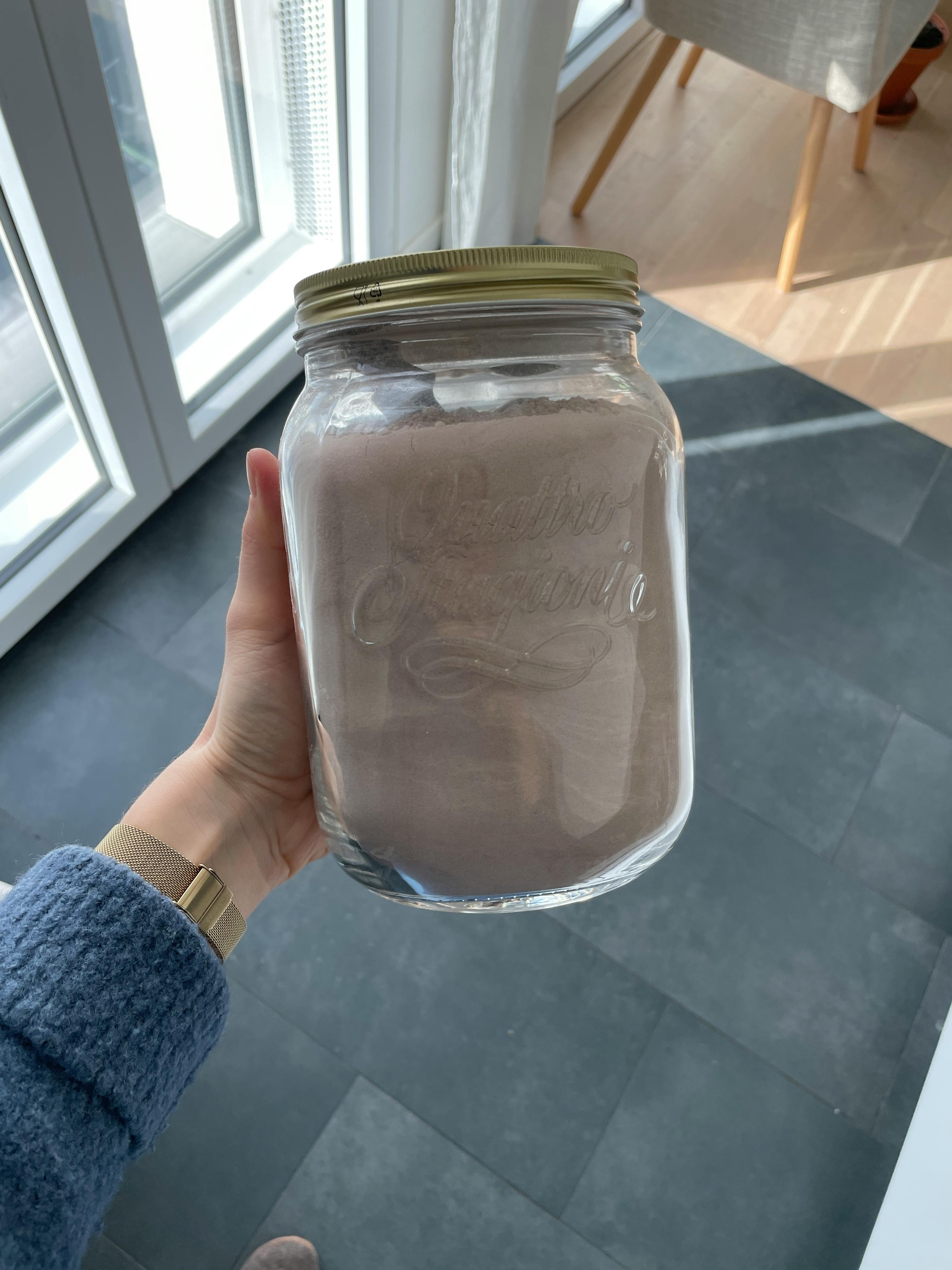 une personne tient un bocal en verre avec un couvercle doré