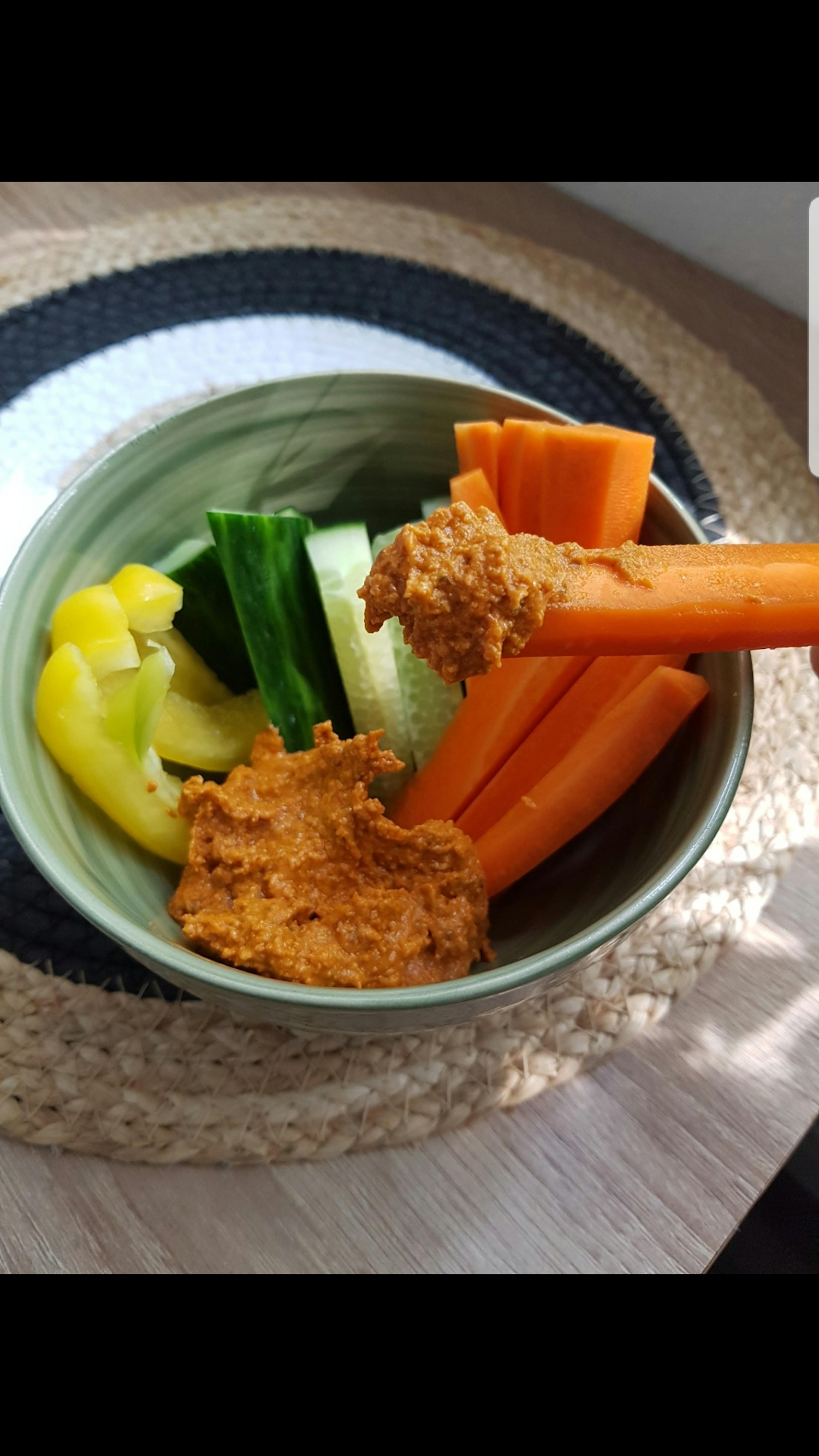 un piatto di verdure con salsa e un pezzo di carota su un bastone