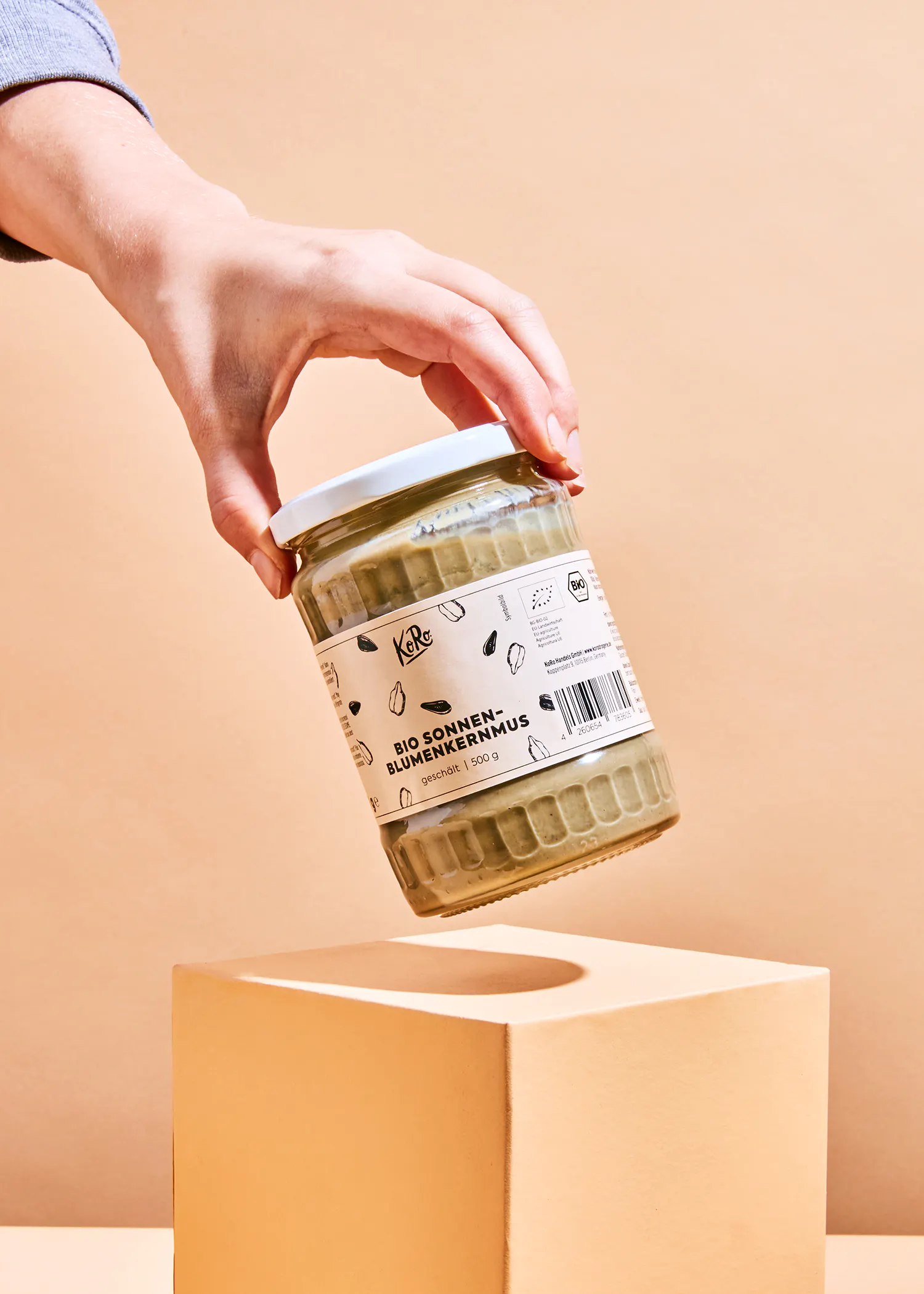 eine hand hält ein glas bio sonnenblumenkernenmus