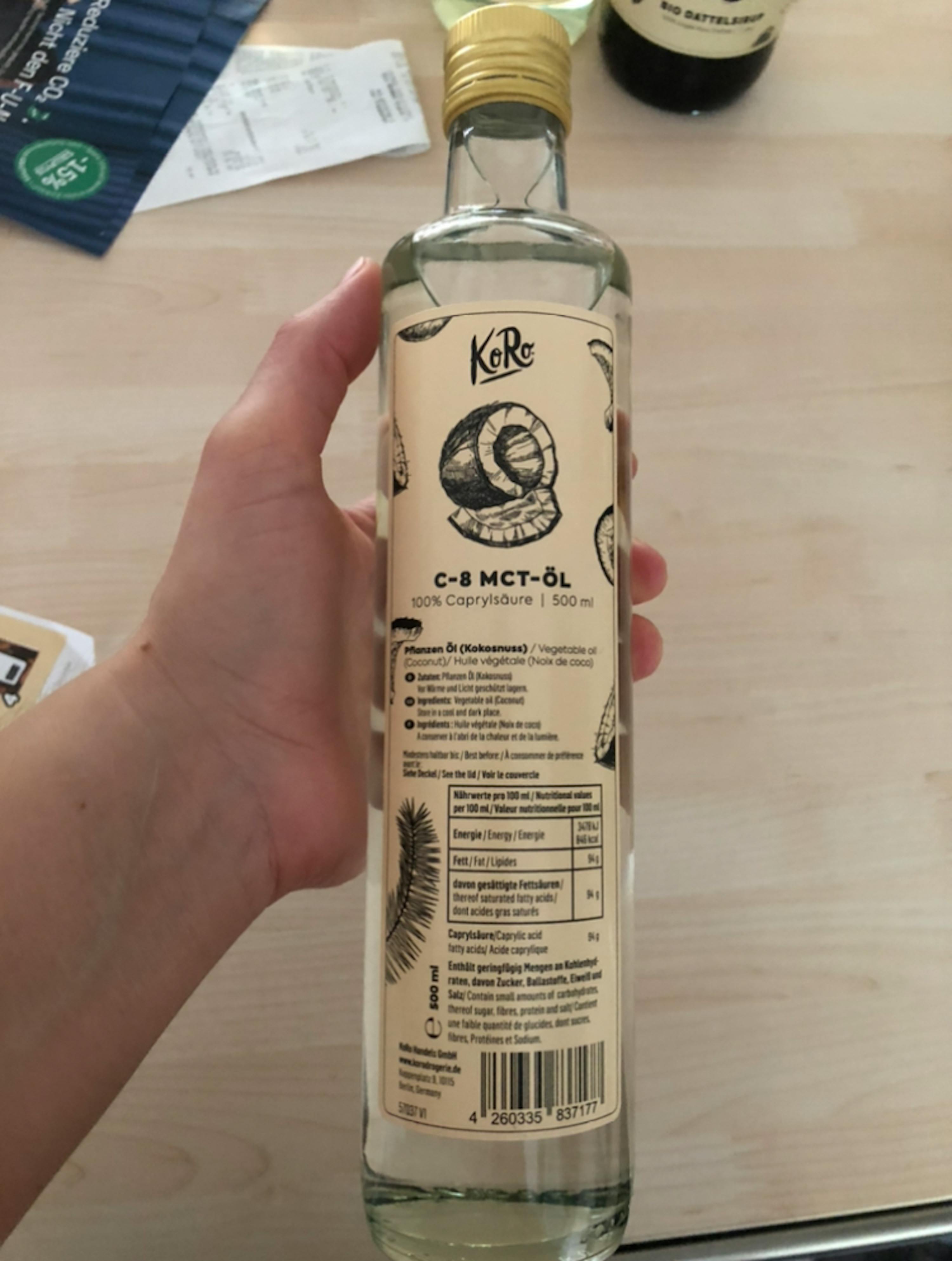 una persona tiene in mano una bottiglia di c-8 mct-ol