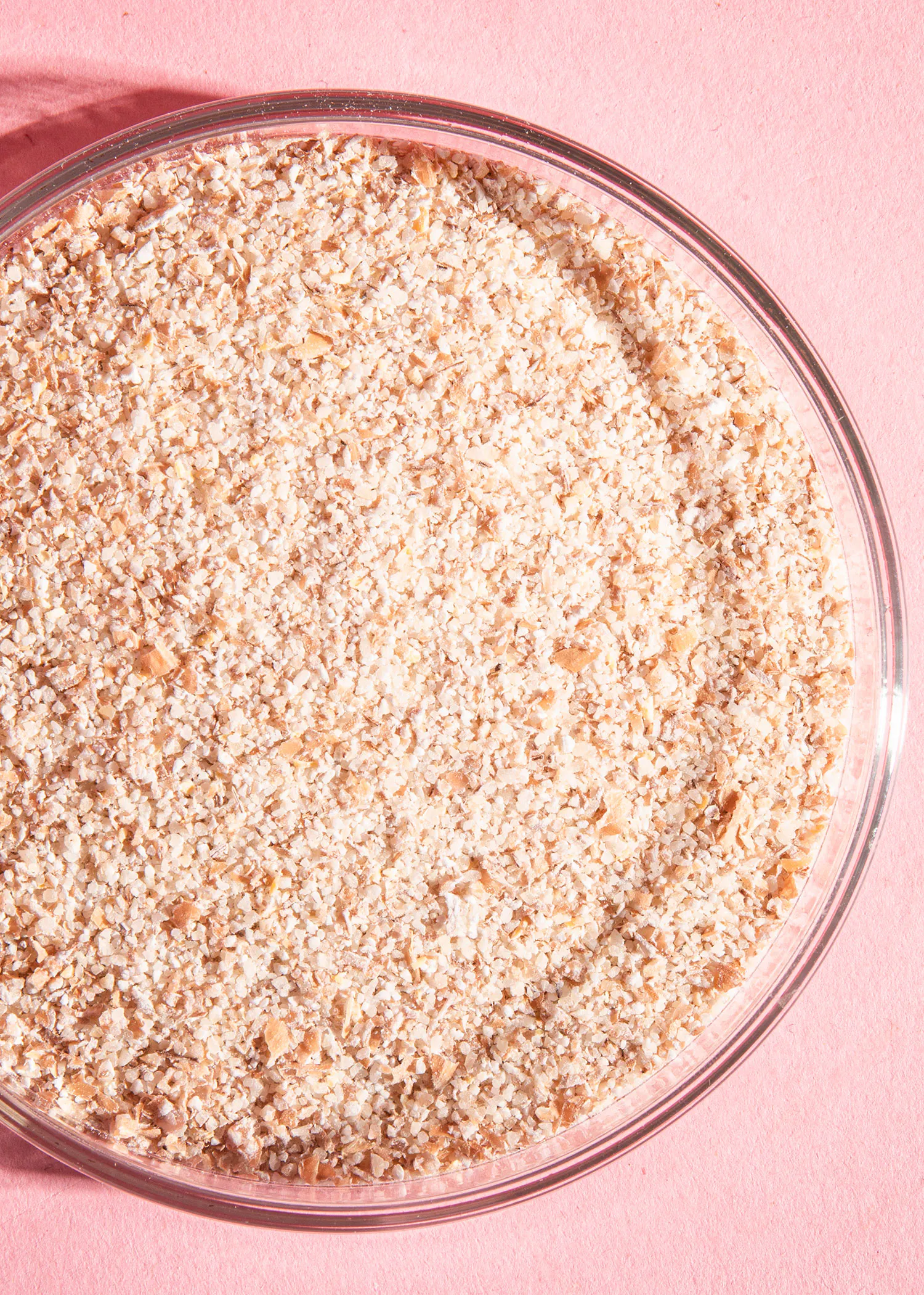 un bol en verre rempli de farine sur une surface rose