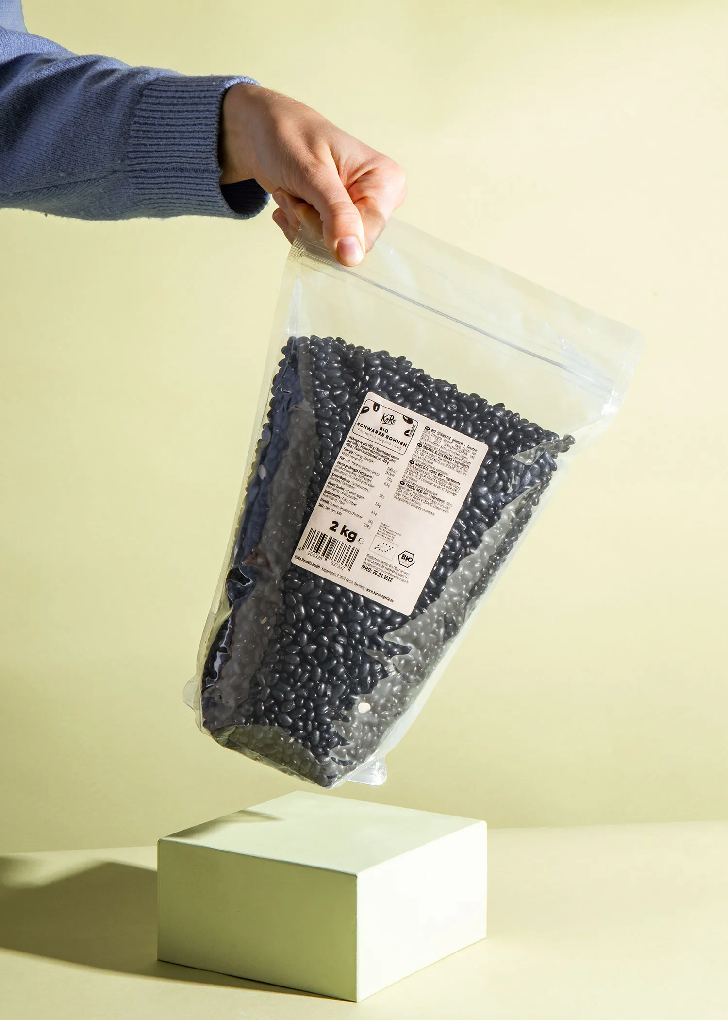 a person is holding a bag of black beans that says 2 kg on it