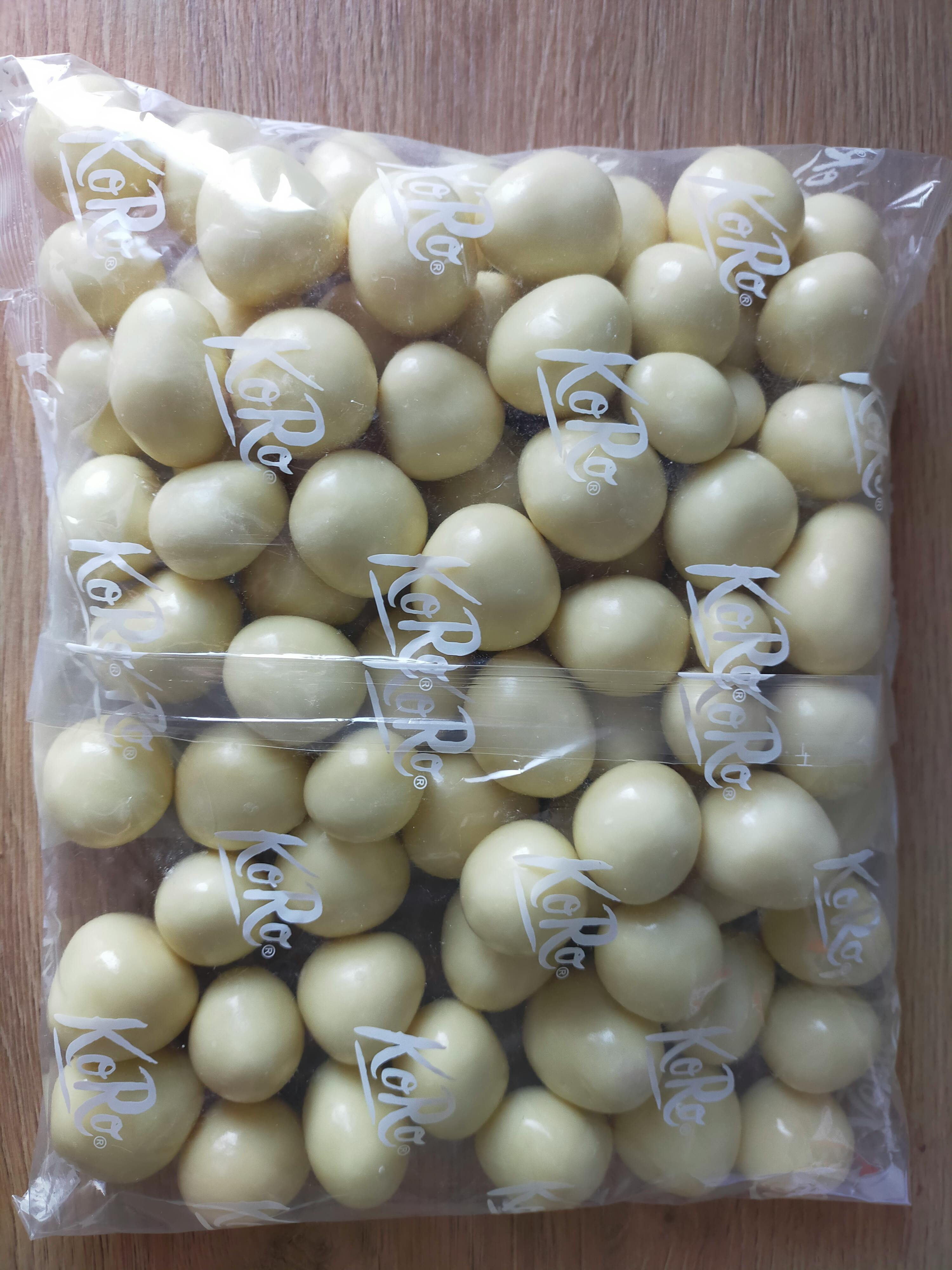 eine transparente tüte voller runder, weißer schokoladenbonbons mit dem koro-logo.