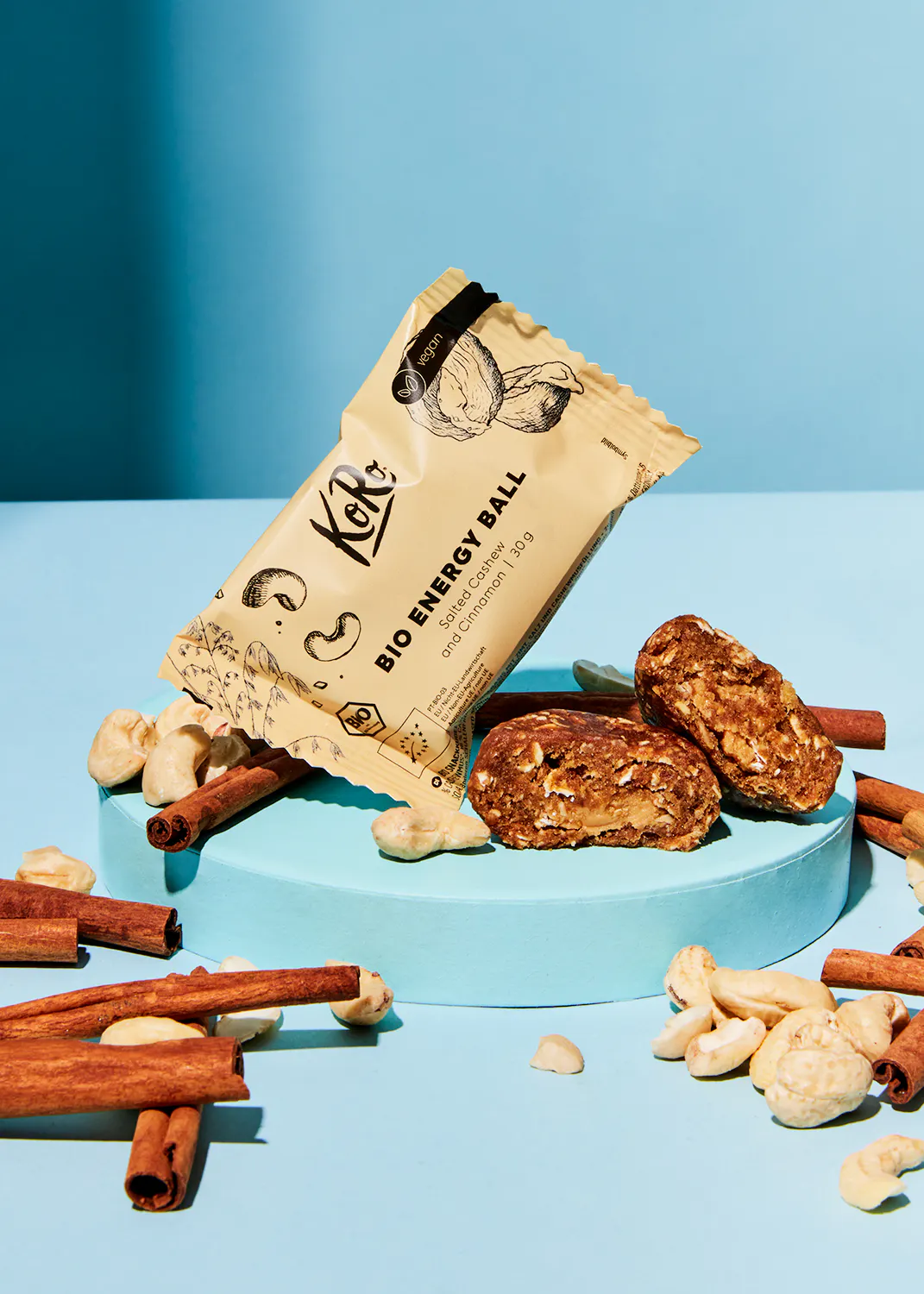 une boule d' énergie bio est posée sur une surface bleue entourée de noix et de bâtons de cannelle