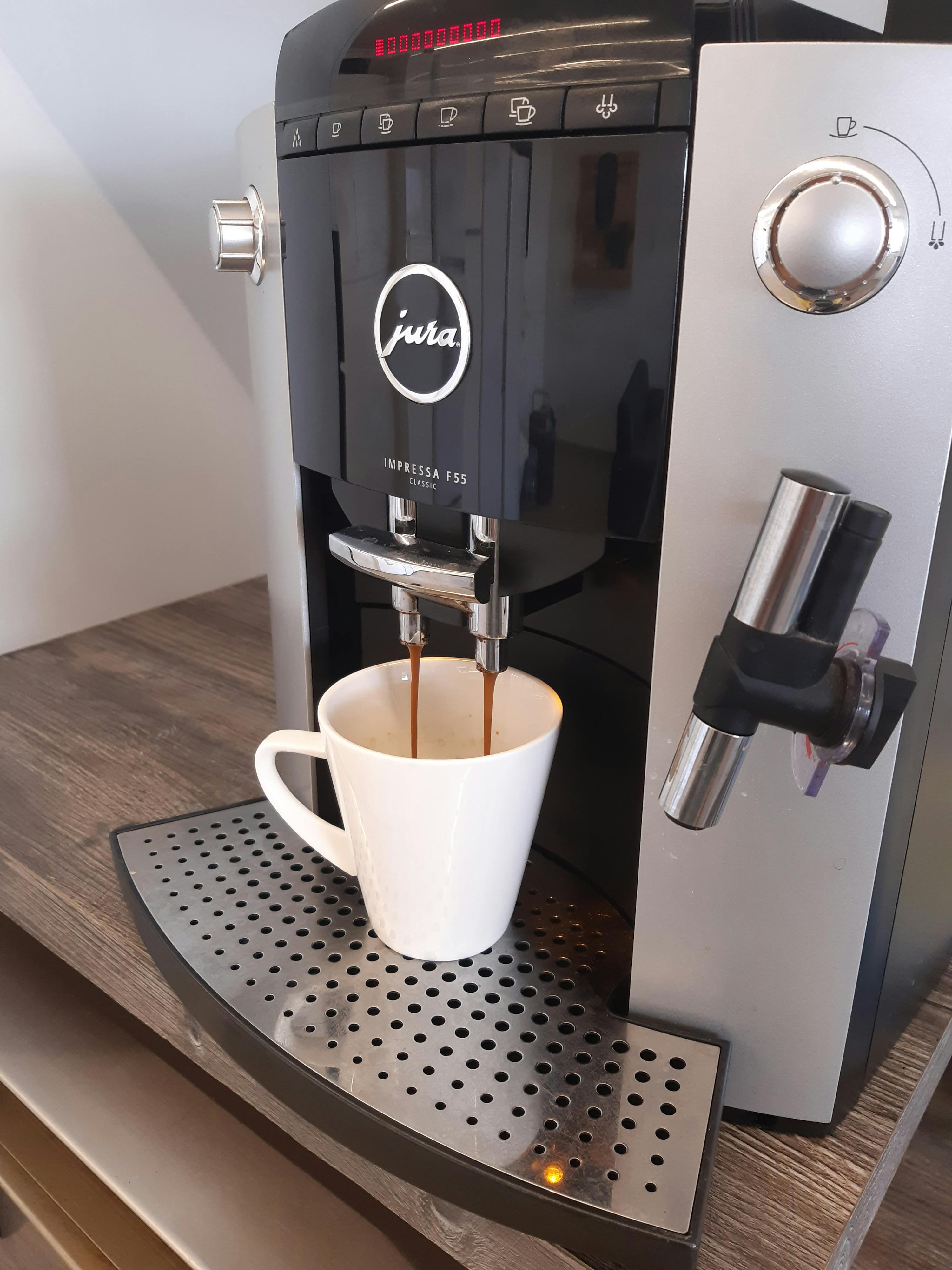 eine schwarze und silberne jura kaffeemaschine mit einer weißen tasse