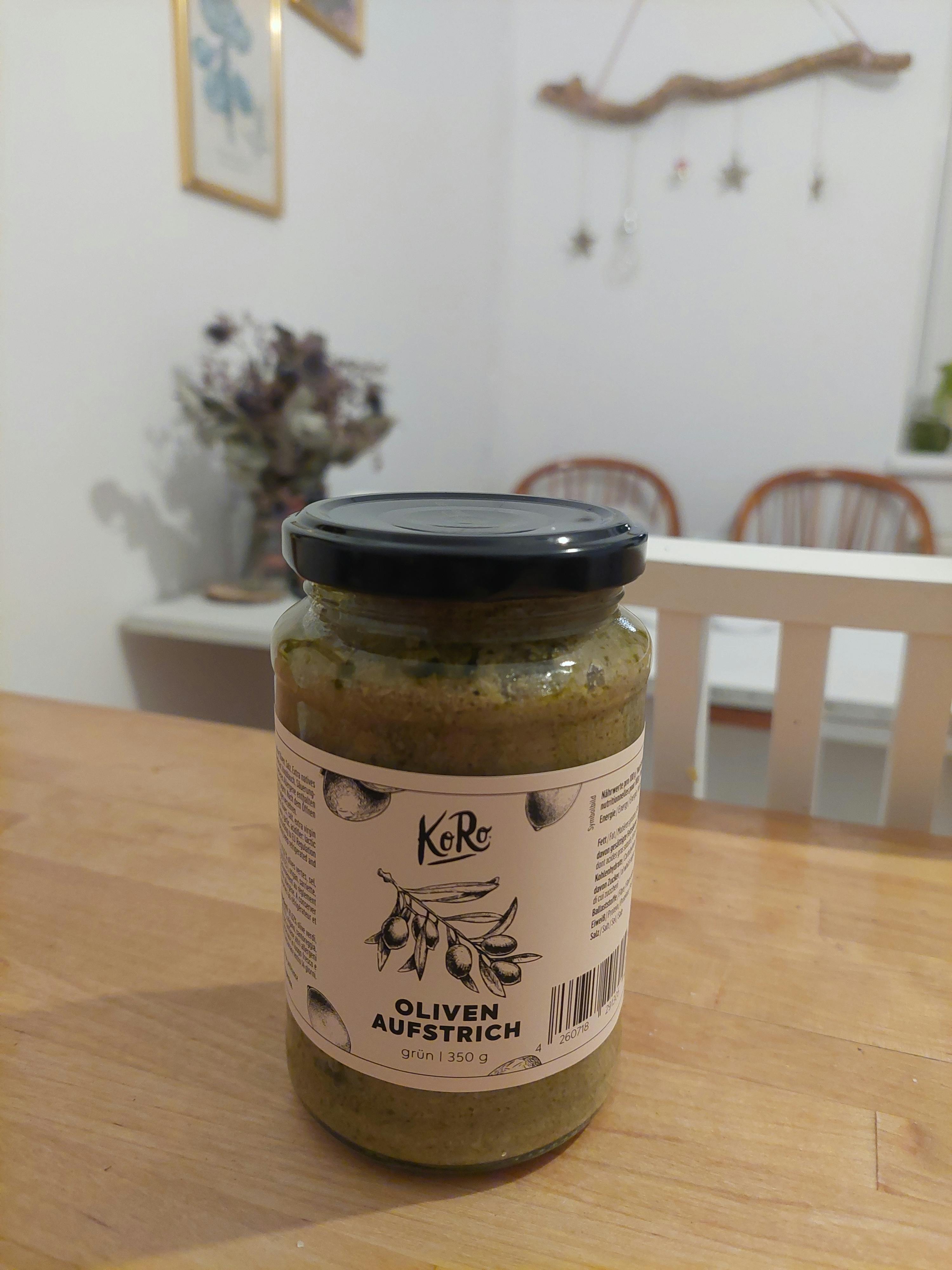 ein Glas oliven aus österreich steht auf einem Holztisch