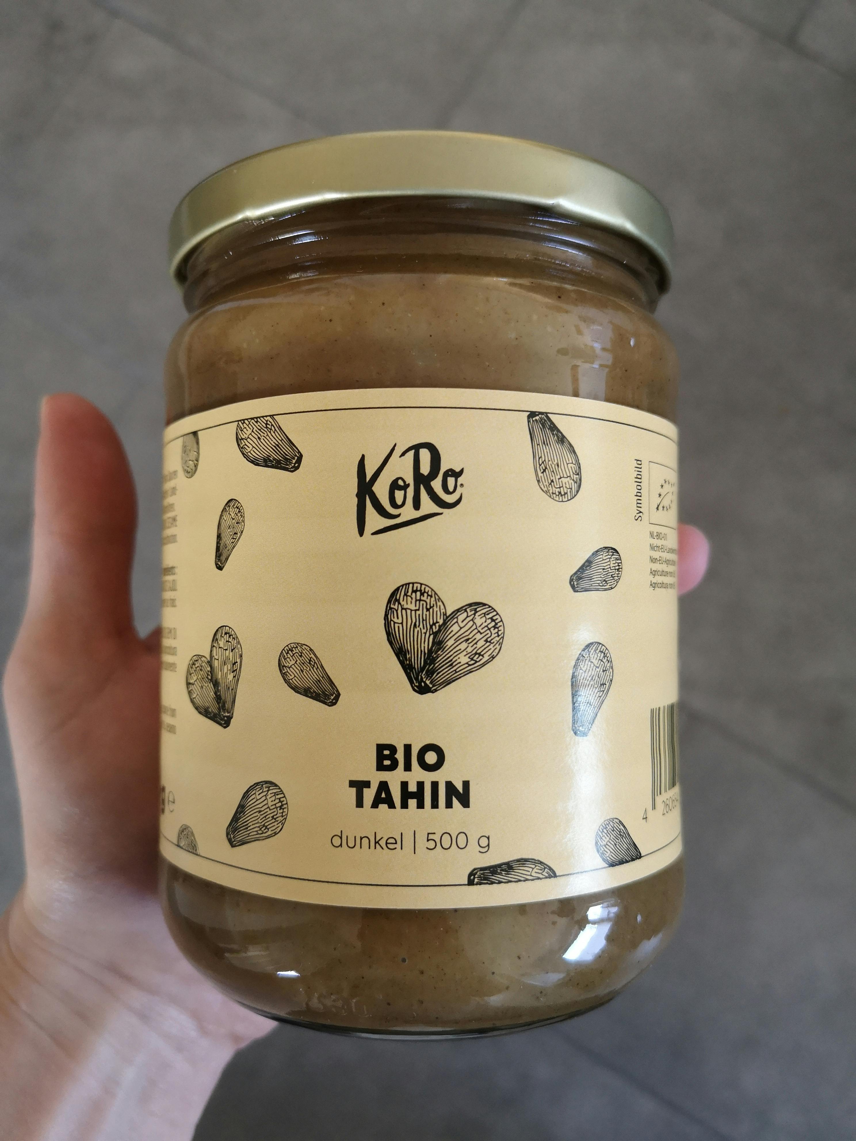 a hand is holding a jar of bio tahin