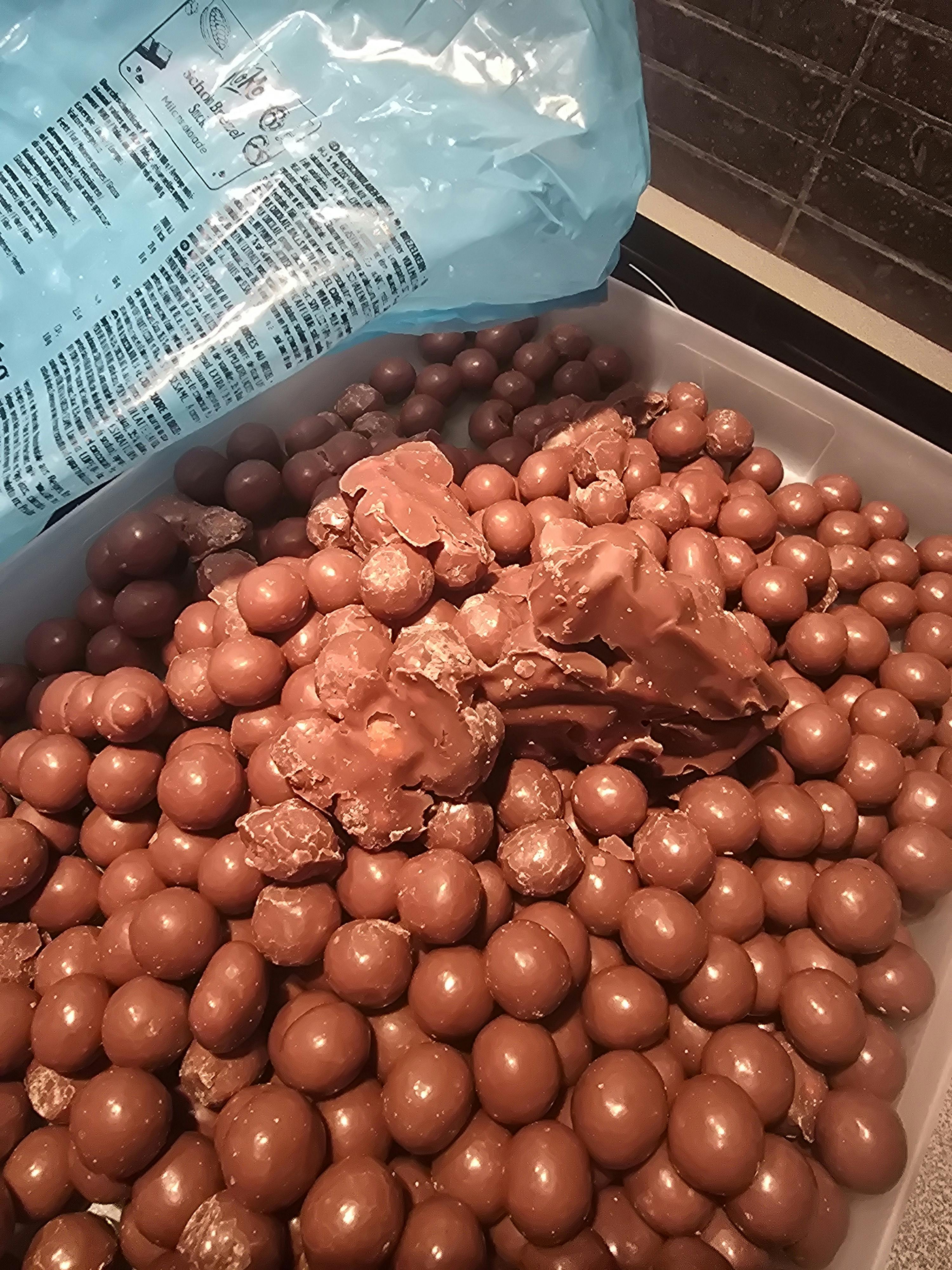 a pile of chocolate balls next to a bag of chocolate