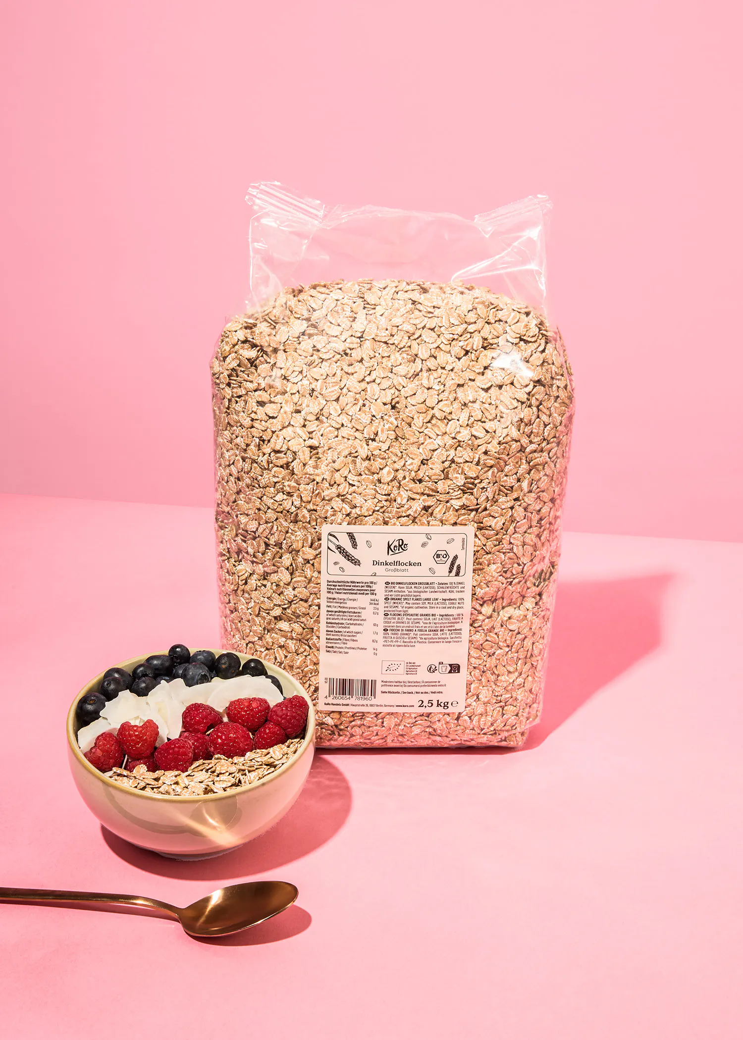 un sac de flocons d' avoine est assis à côté d' un bol de flocons d' avoine et d' une cuillère